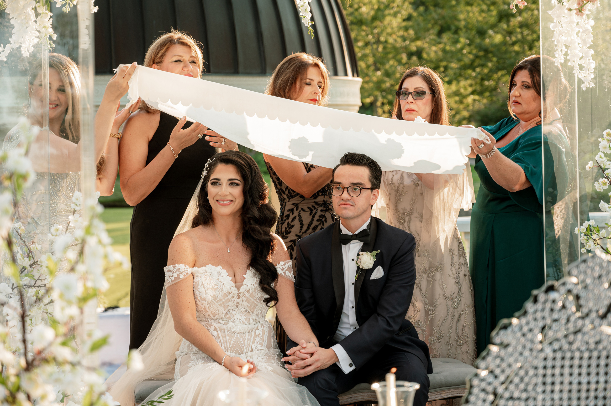 a bride and groom sitting on a bench with their wedding party