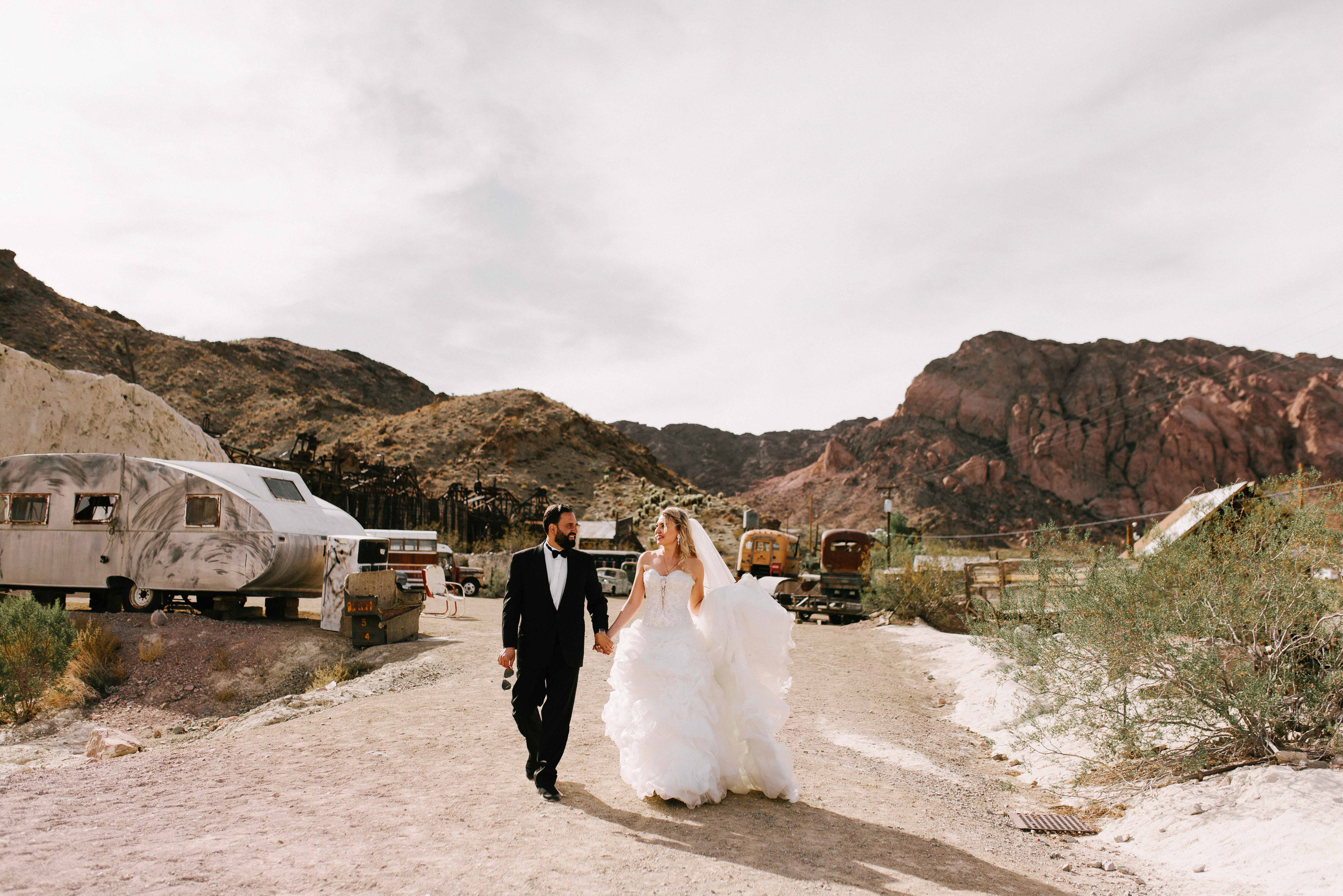 a bride and groom walking down a dirt road