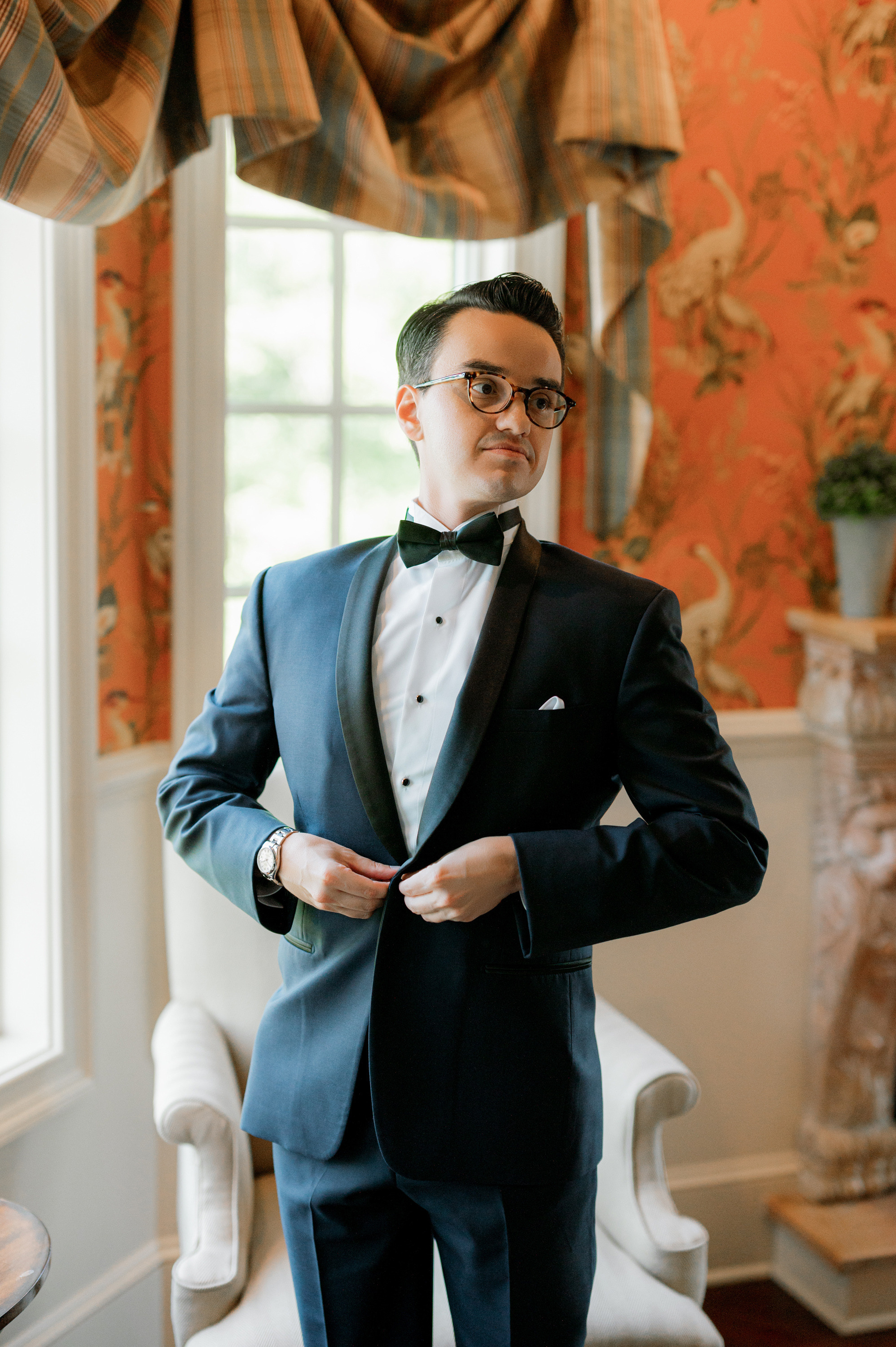 a man in a suit and bow tie standing in a room