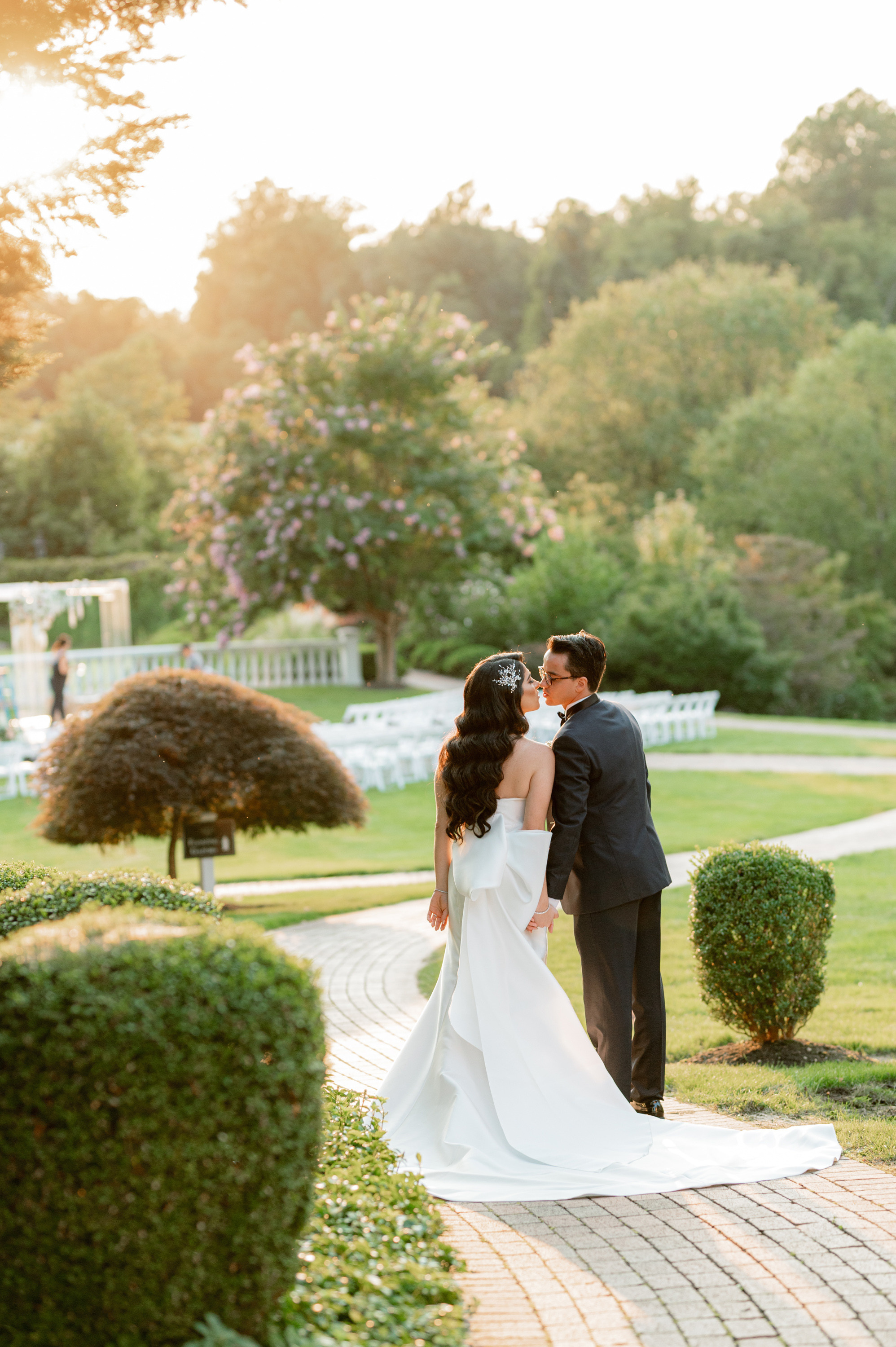 a bride and groom kissing in the gardens at their wedding