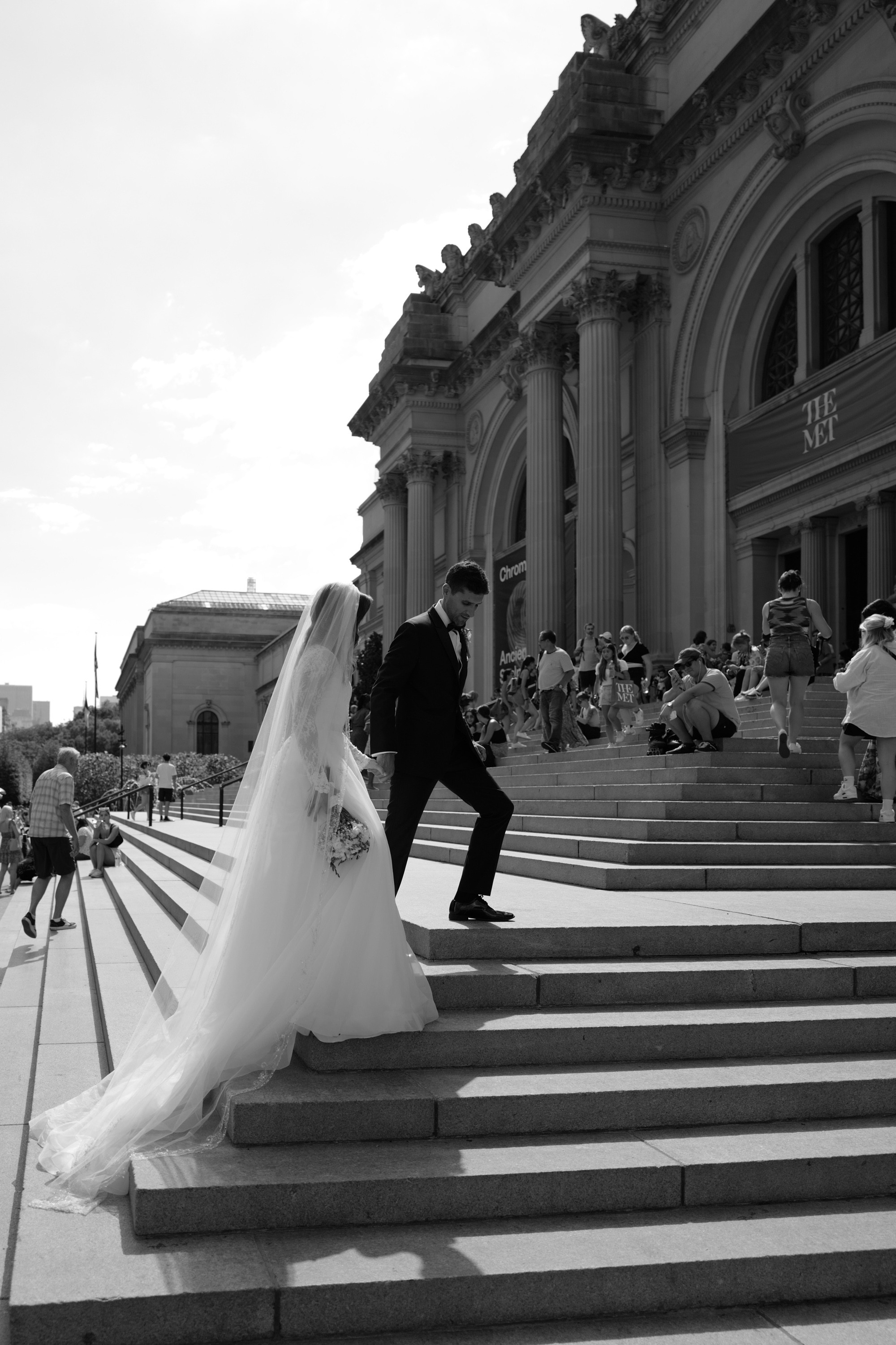 a bride and groom sitting on the steps of a building