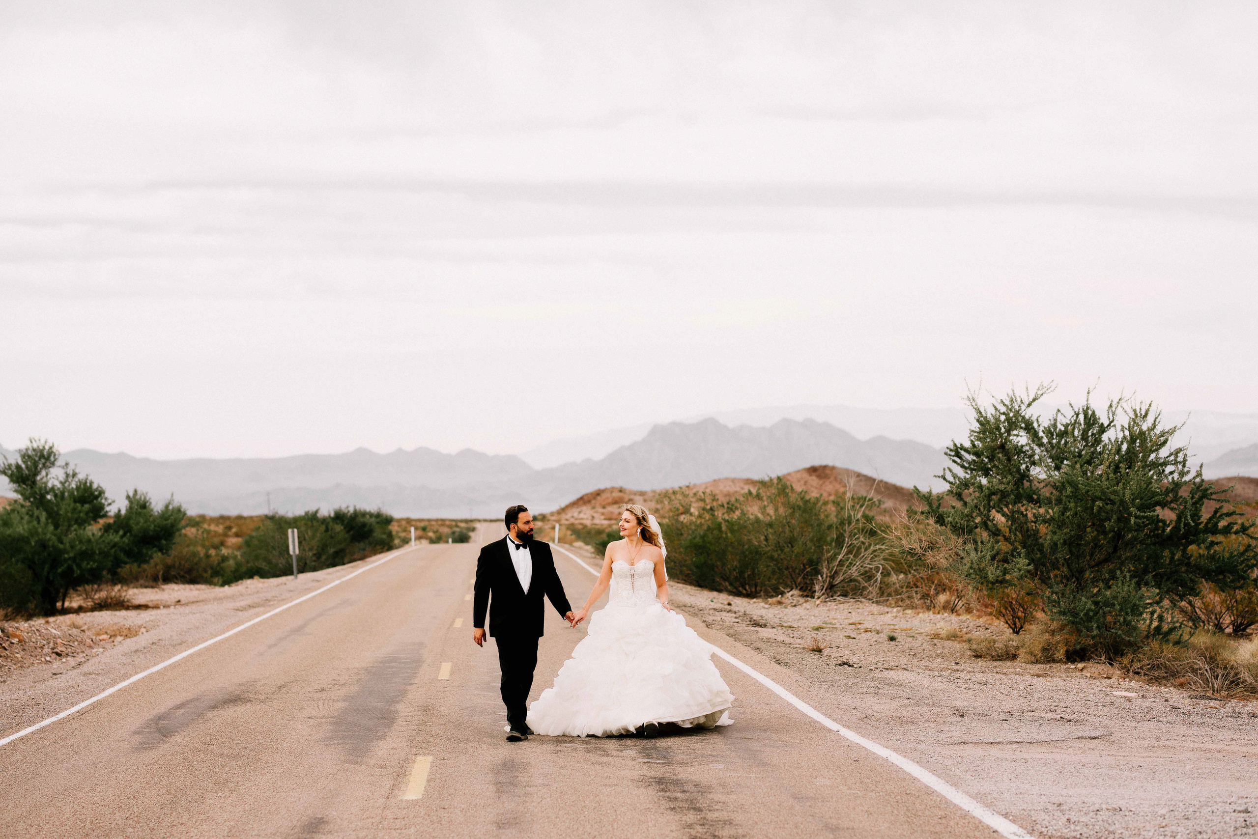 a bride and groom walking down the road