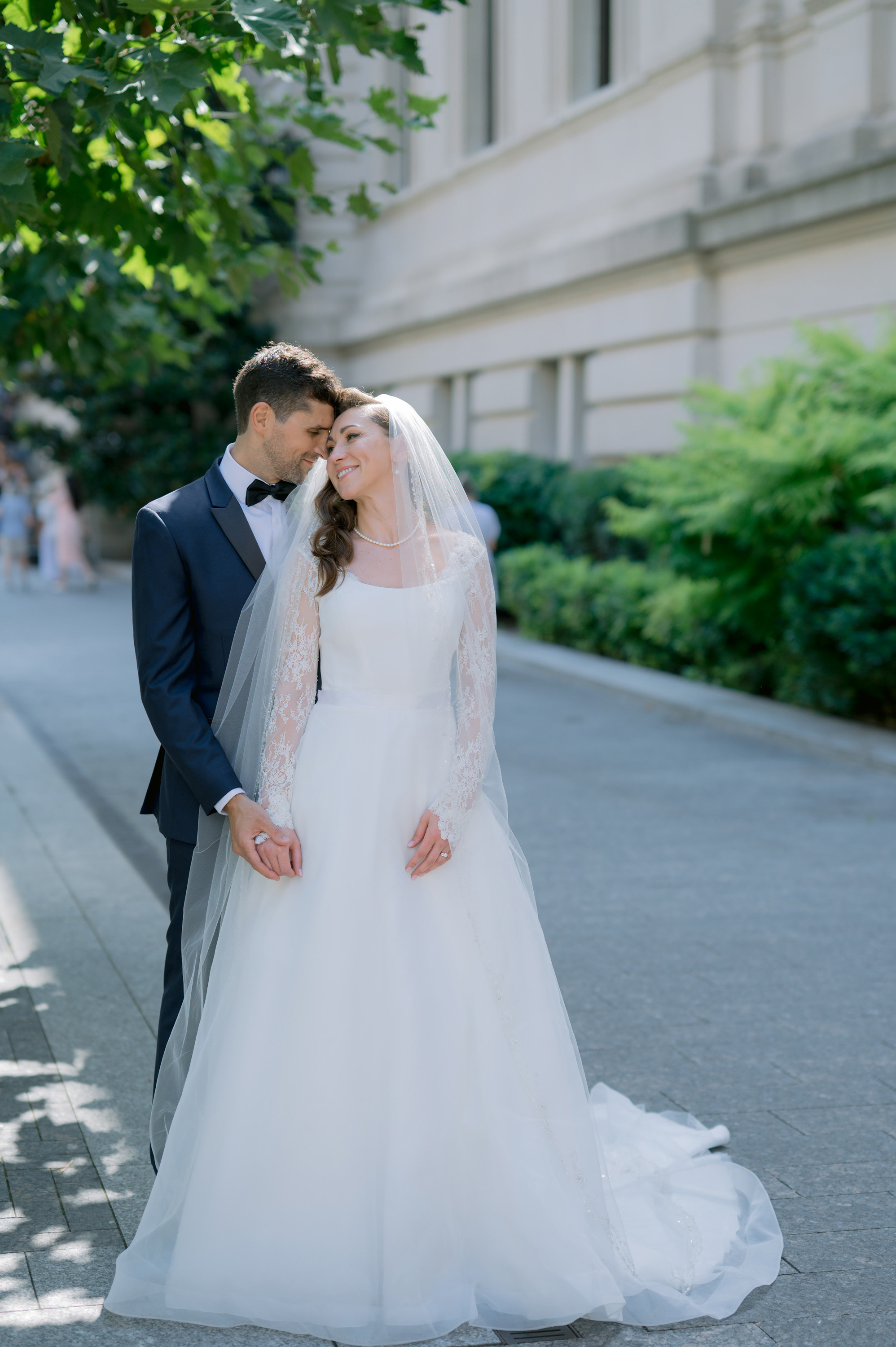 a bride and groom pose for a photo in front of a building