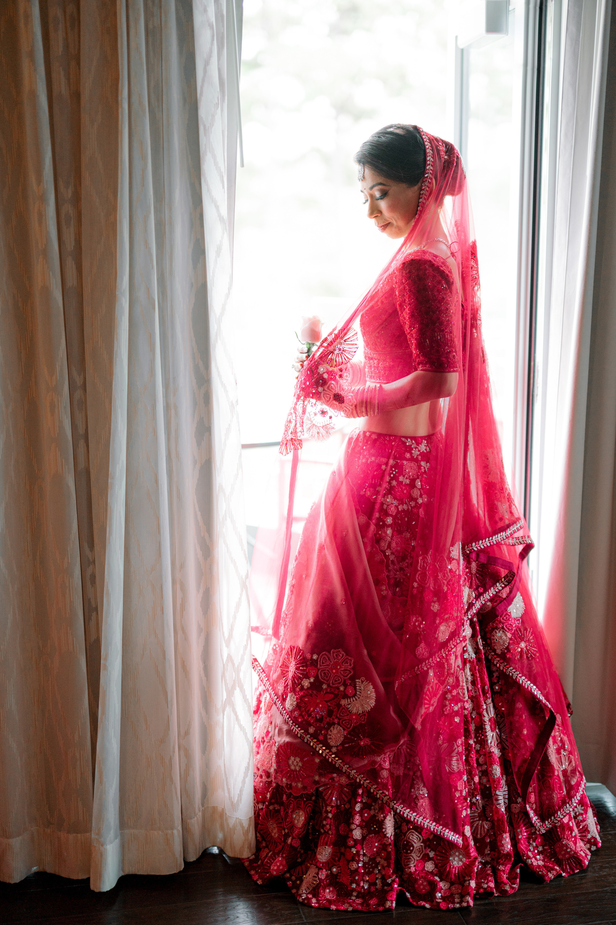 a woman in a red dress standing by a window