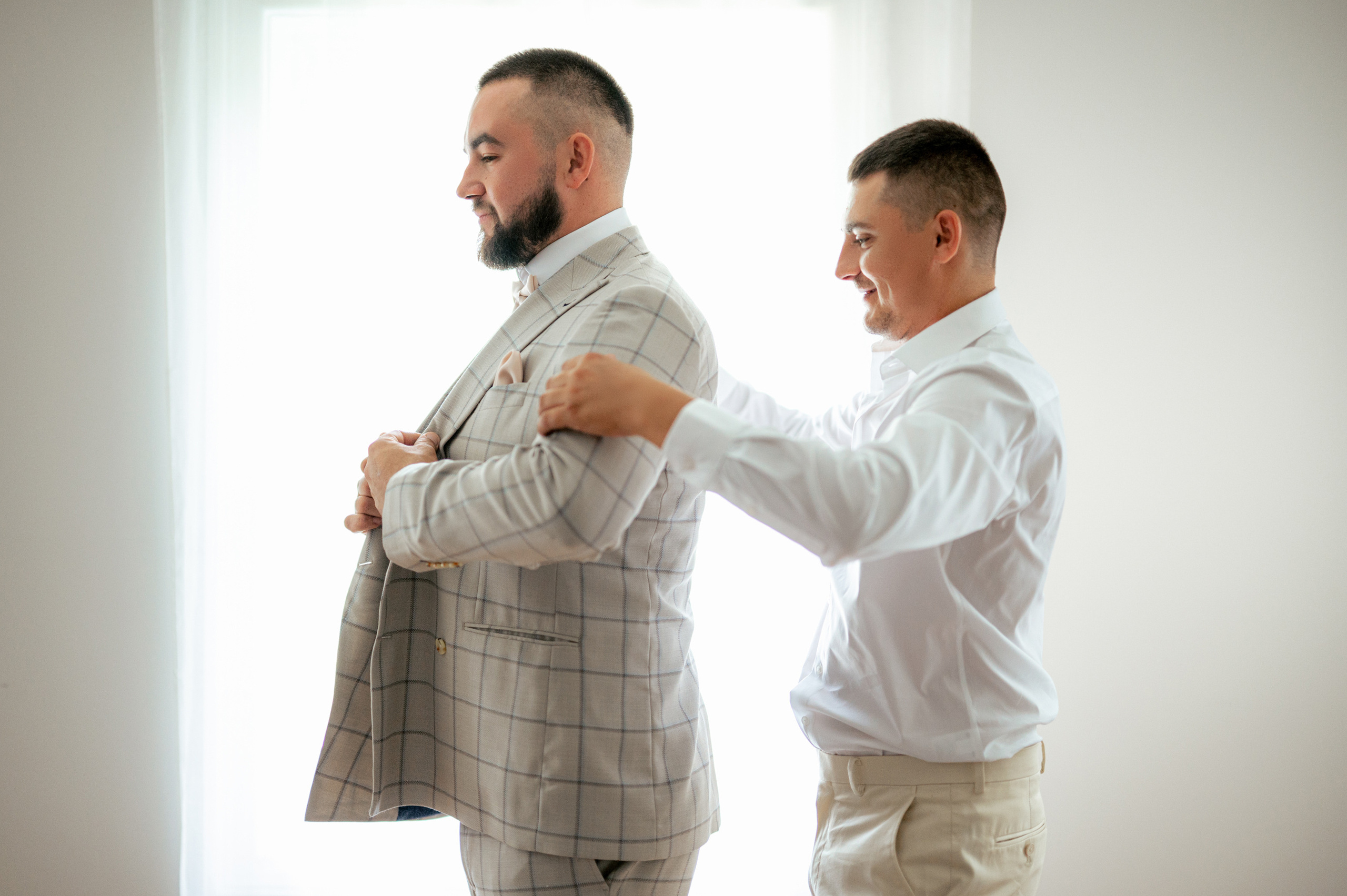 two men in suits are fixing their ties