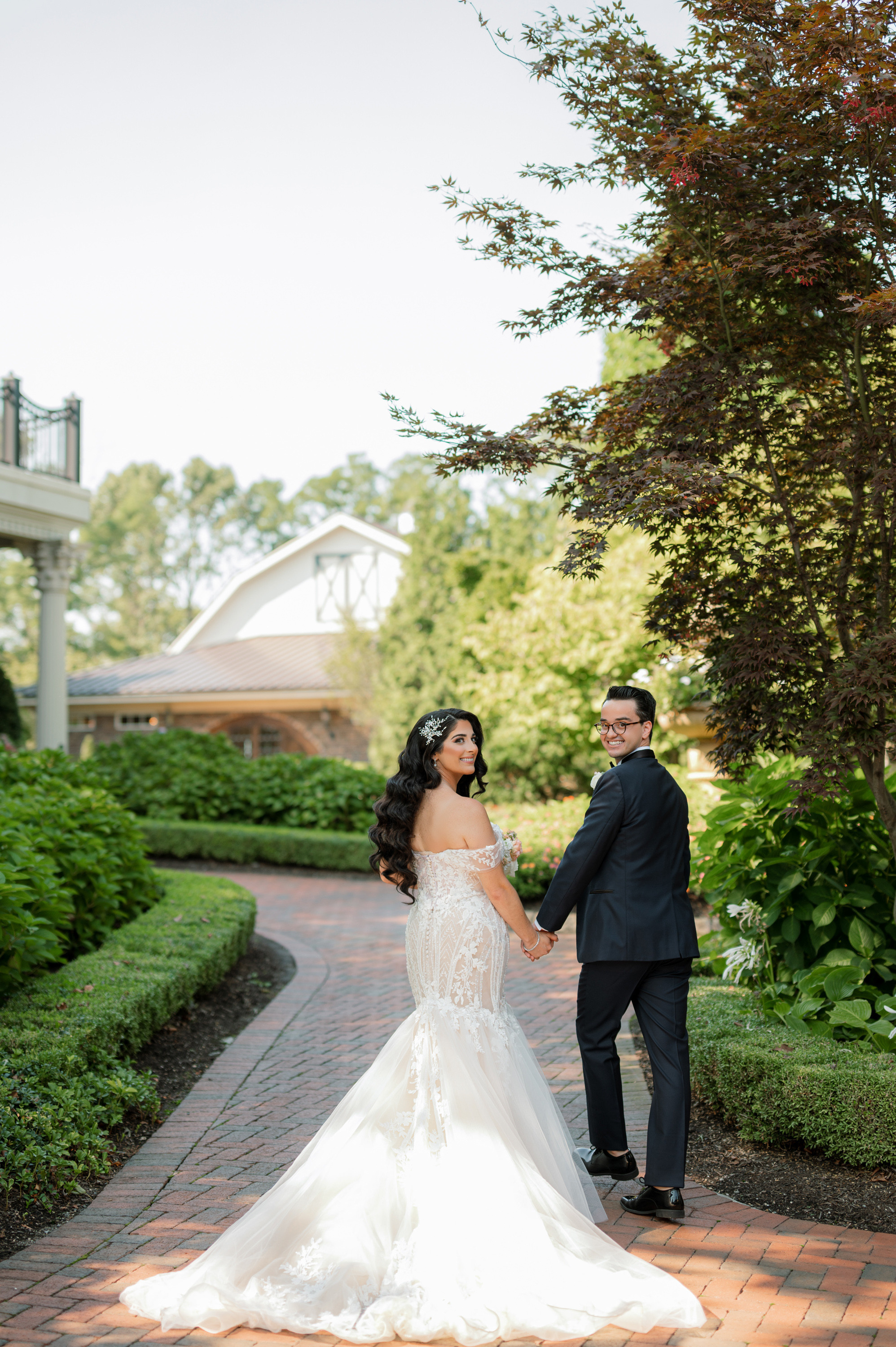 a bride and groom walking down a brick path