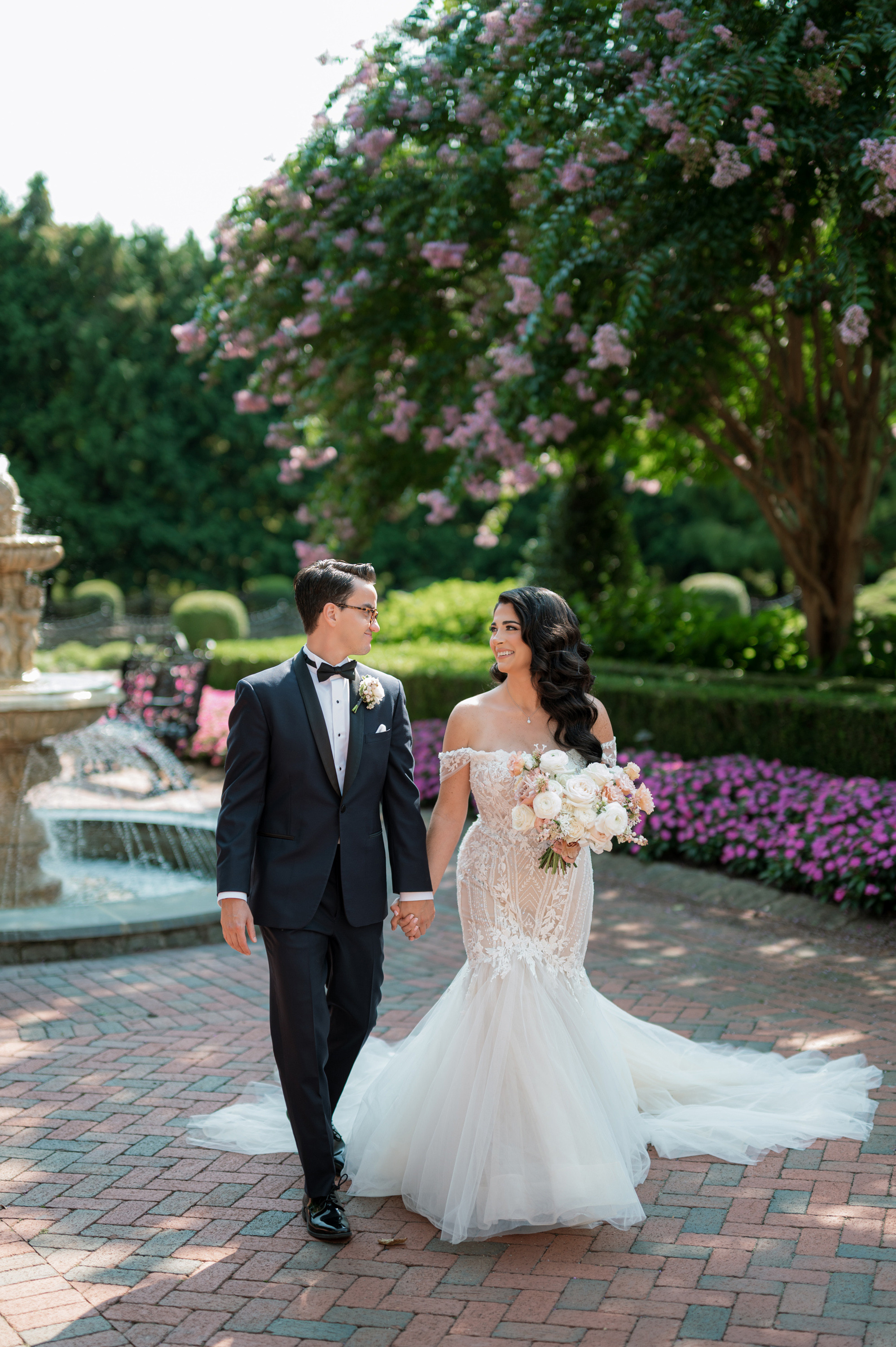 a bride and groom walking through the gardens at their wedding