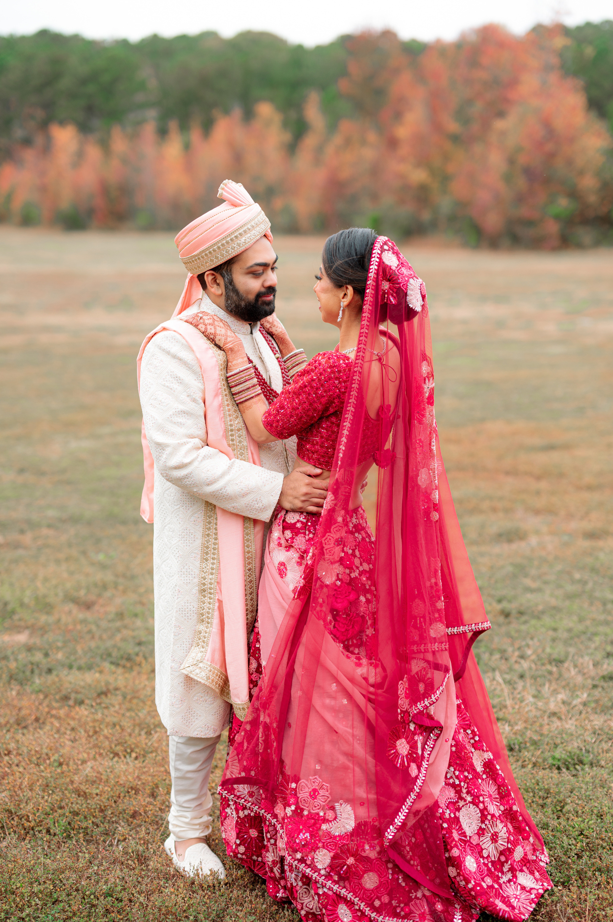 a bride and groom pose for a photo in a field