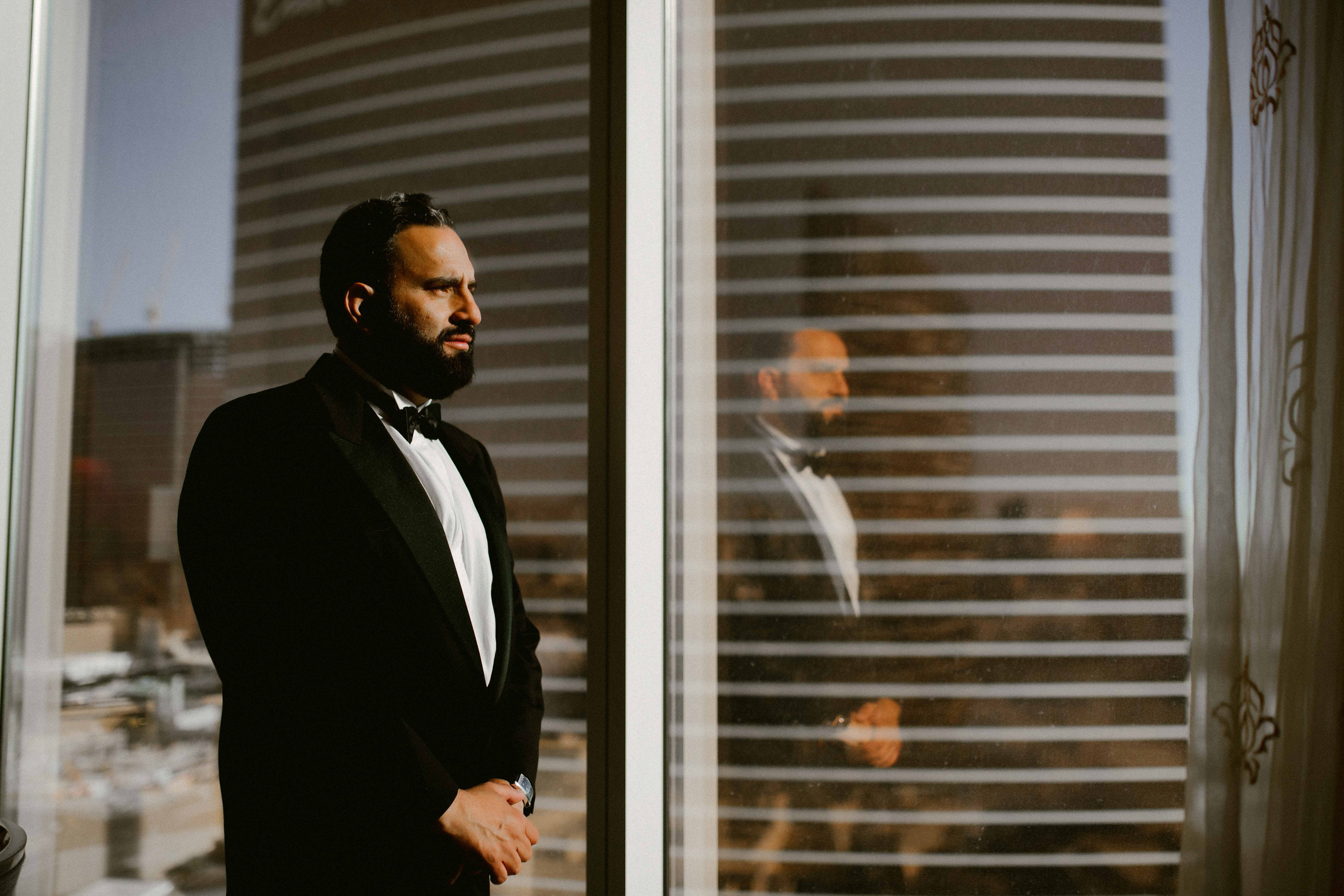 a man in a tuxed suit looking out a window