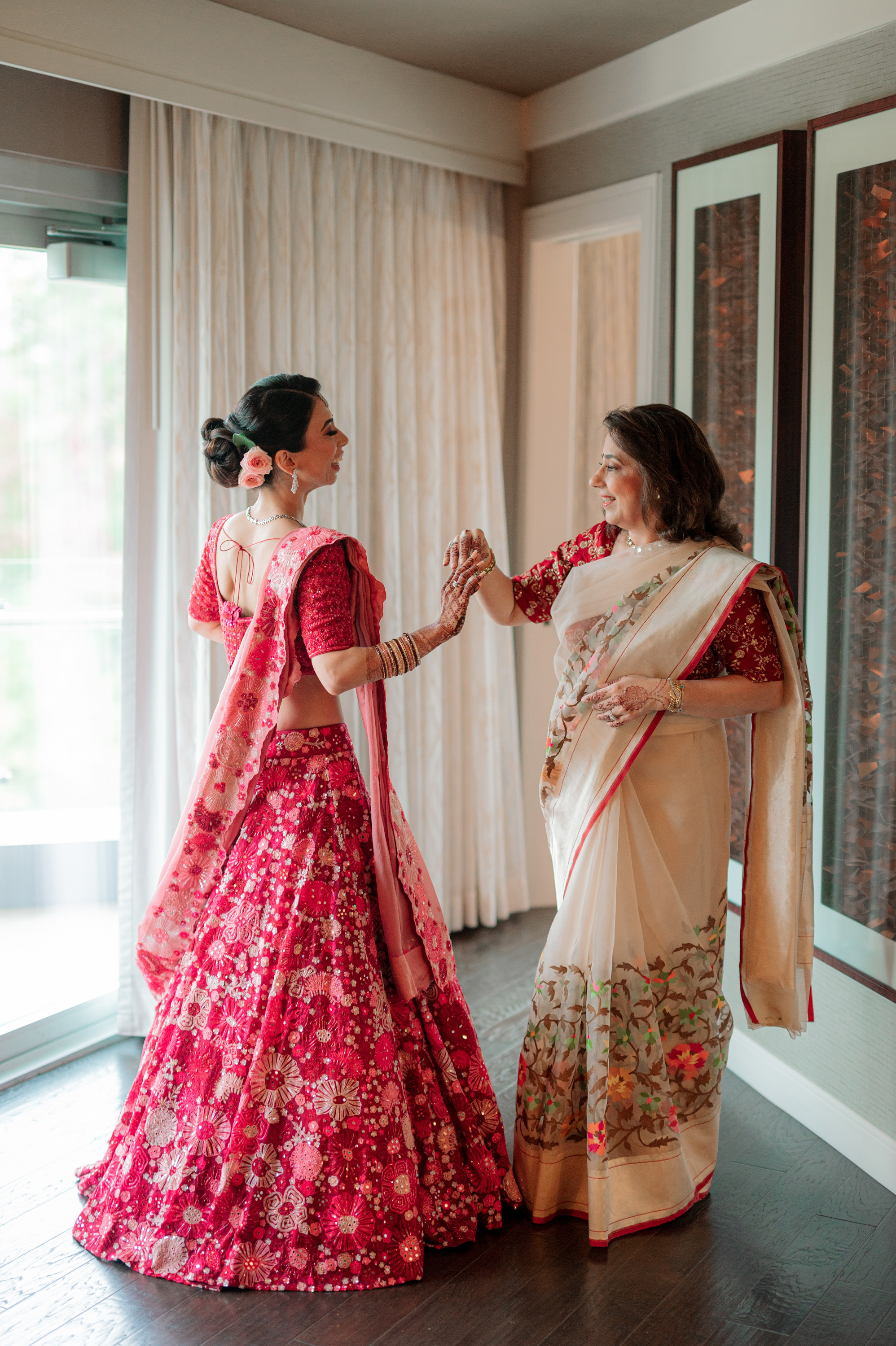 two women in traditional indian clothing standing in front of a window