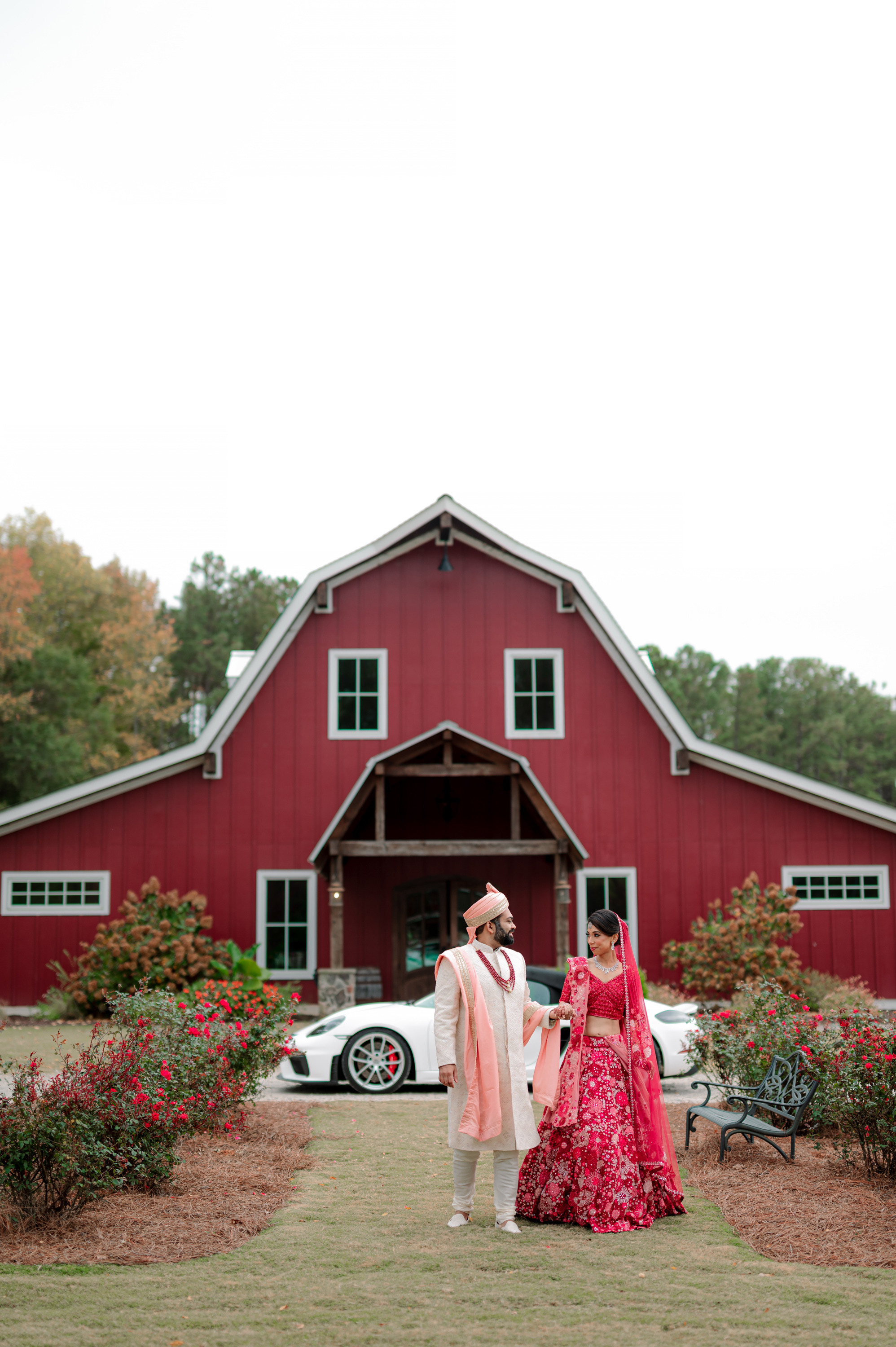 a couple standing in front of a red barn
