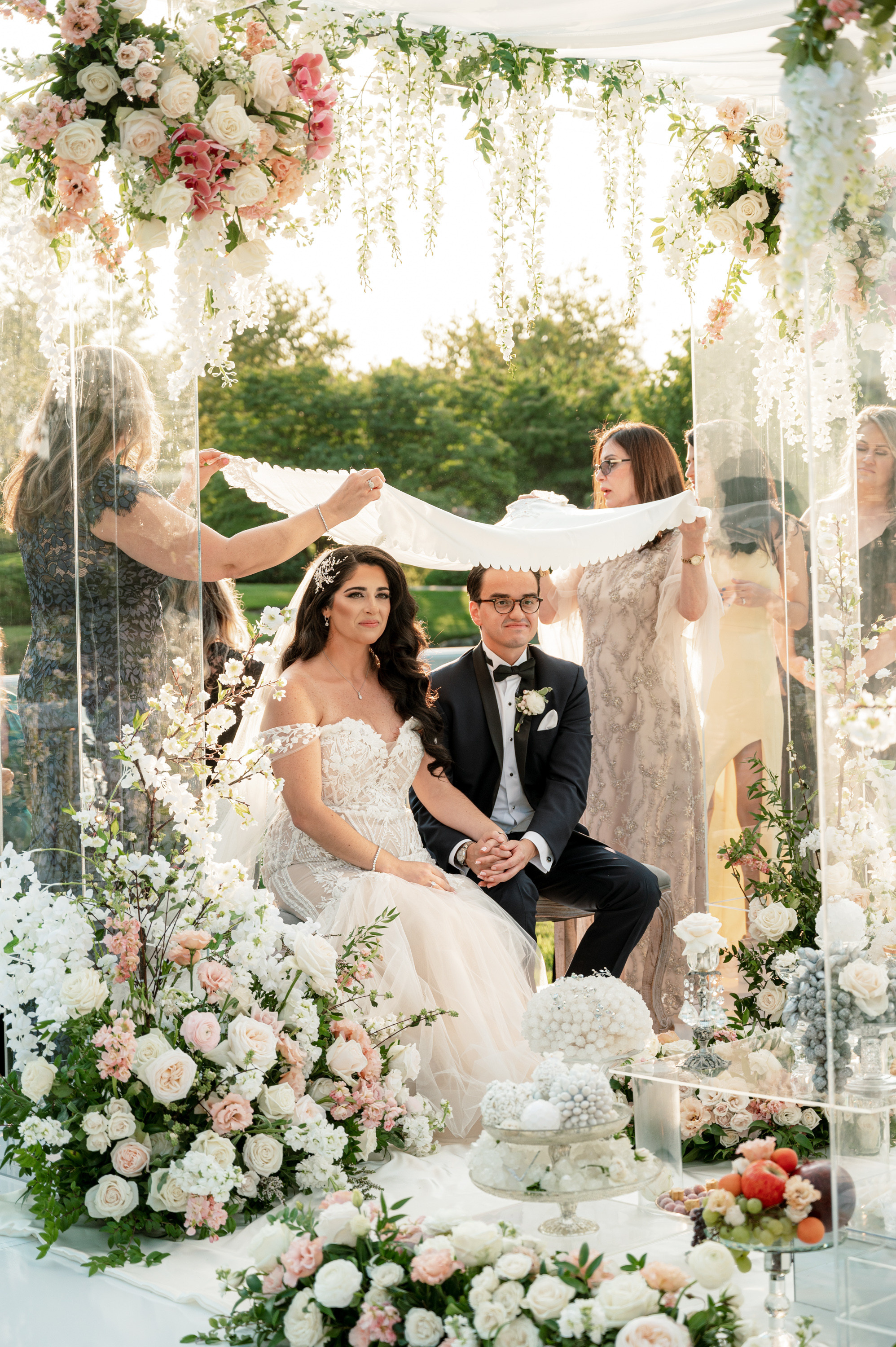 a couple sitting under a canopy with flowers