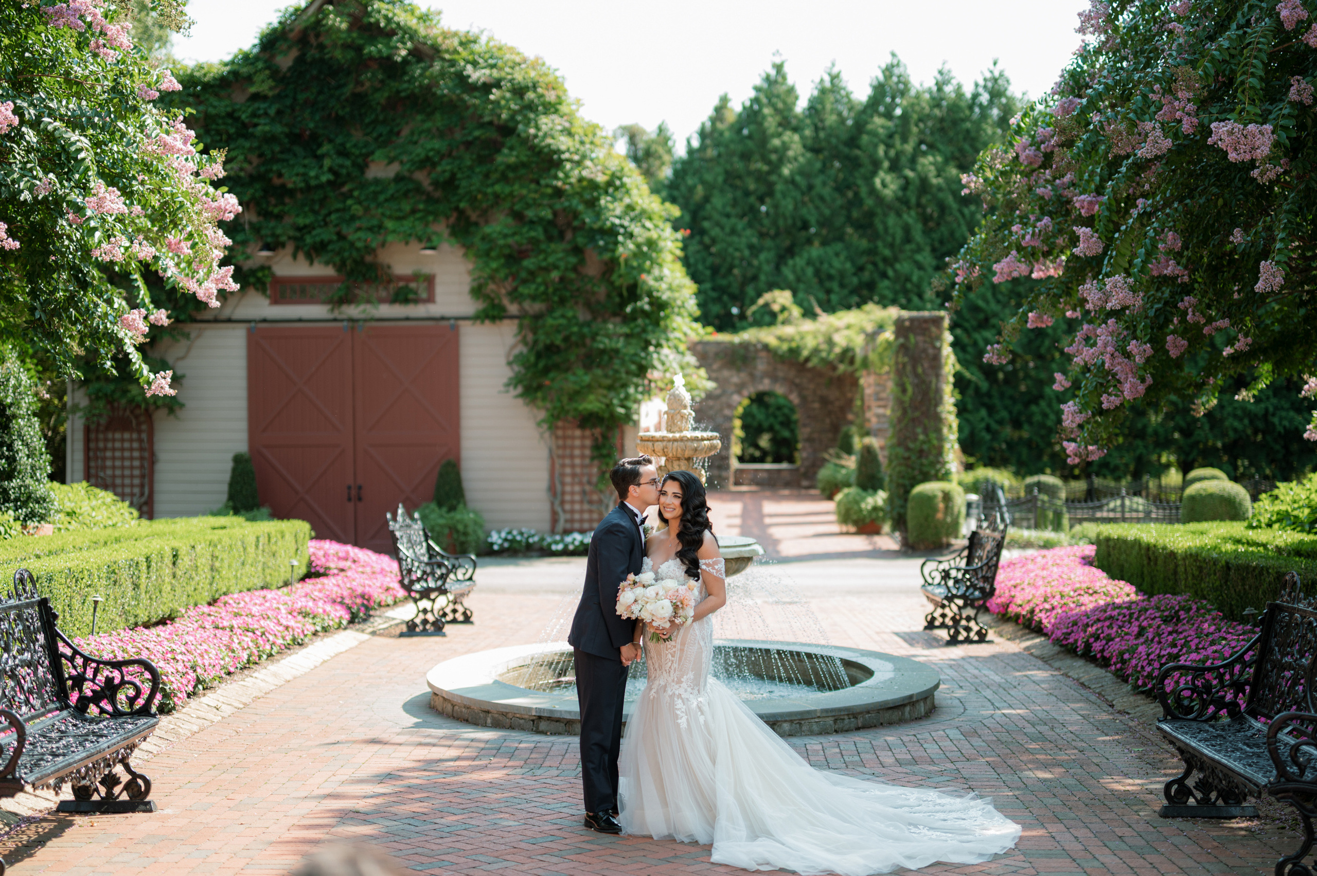a bride and groom pose for a photo in front of a fountain