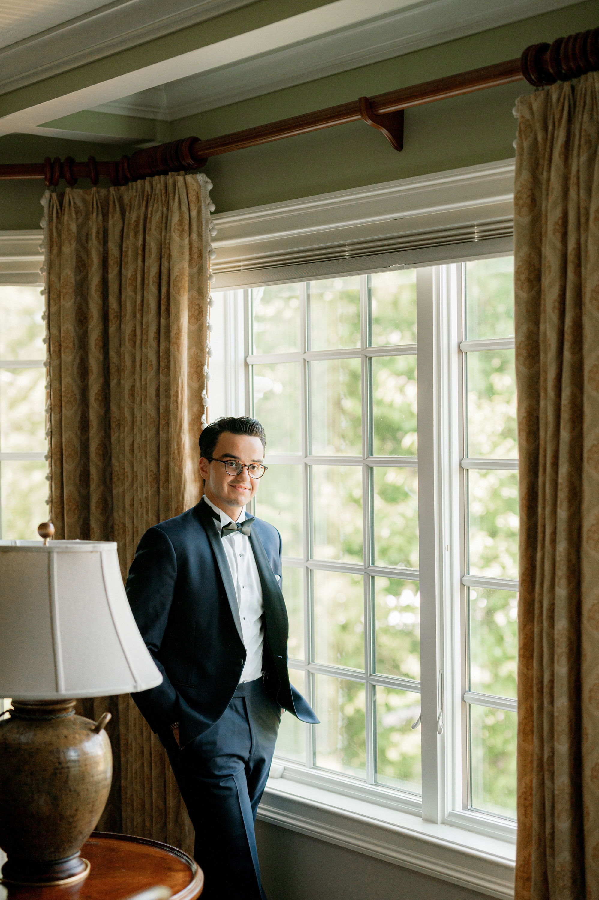 a man in a suit standing by a window