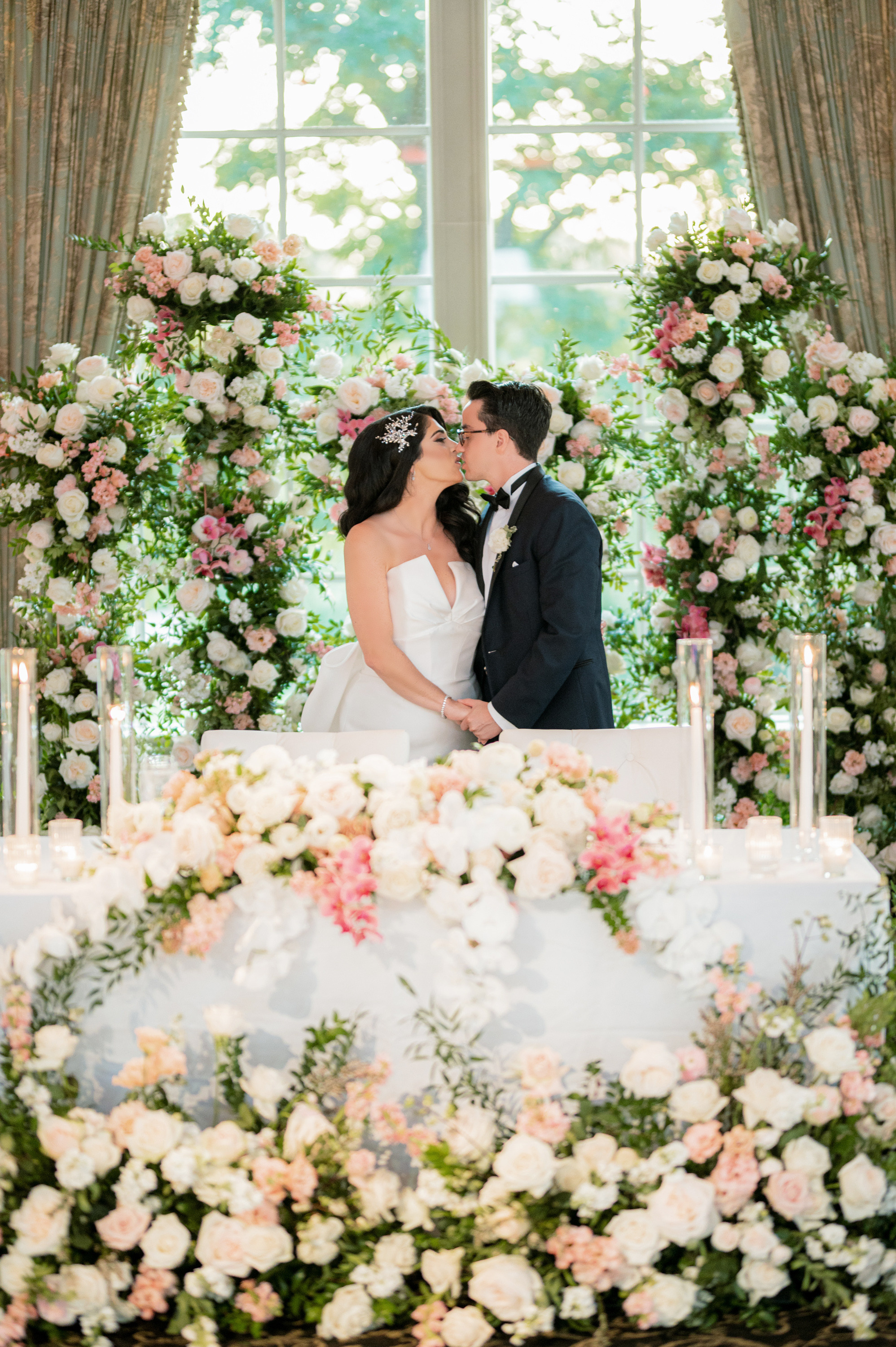 a bride and groom kissing in front of a floral arch