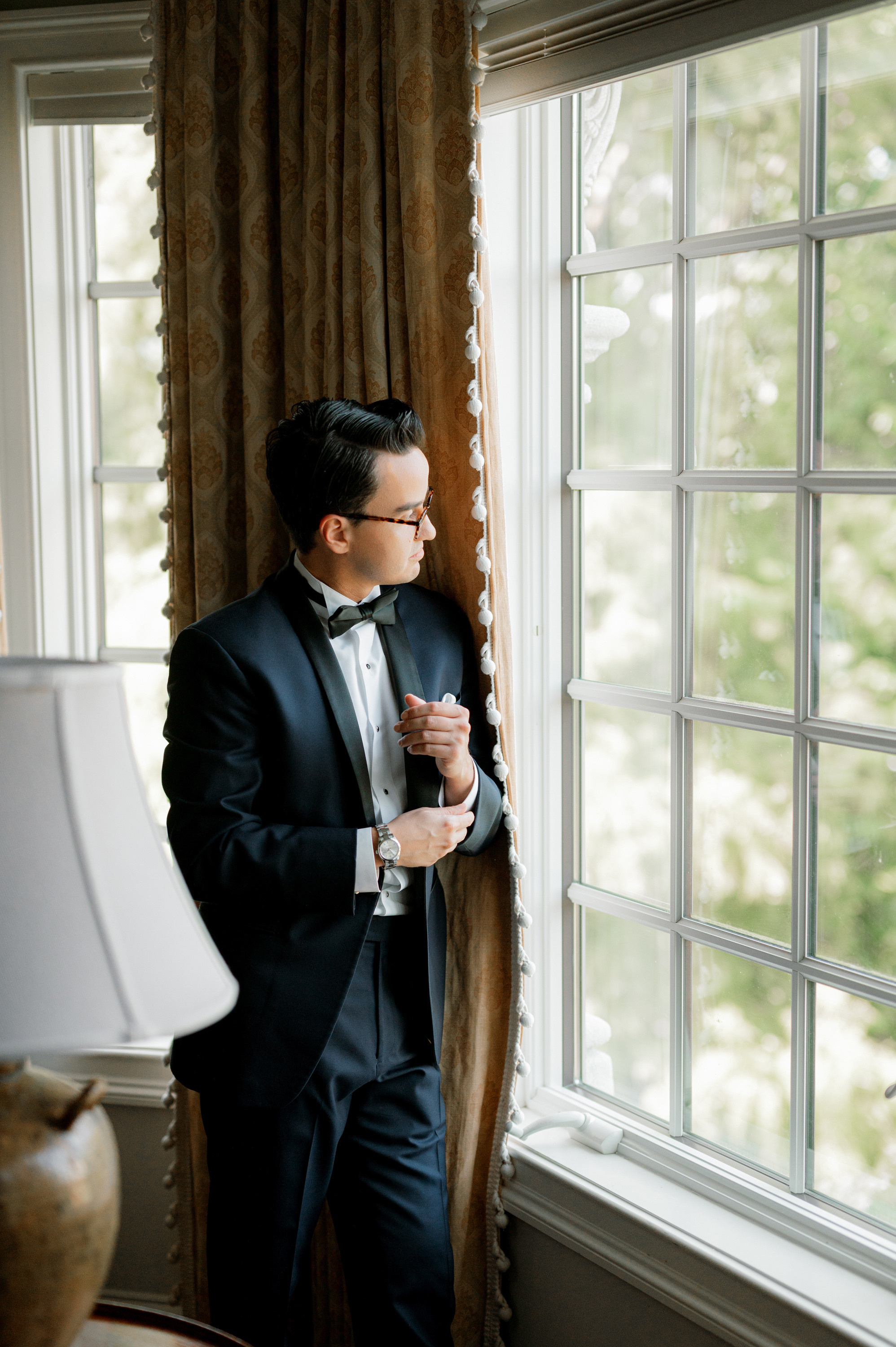 a man in a suit and tie standing by a window