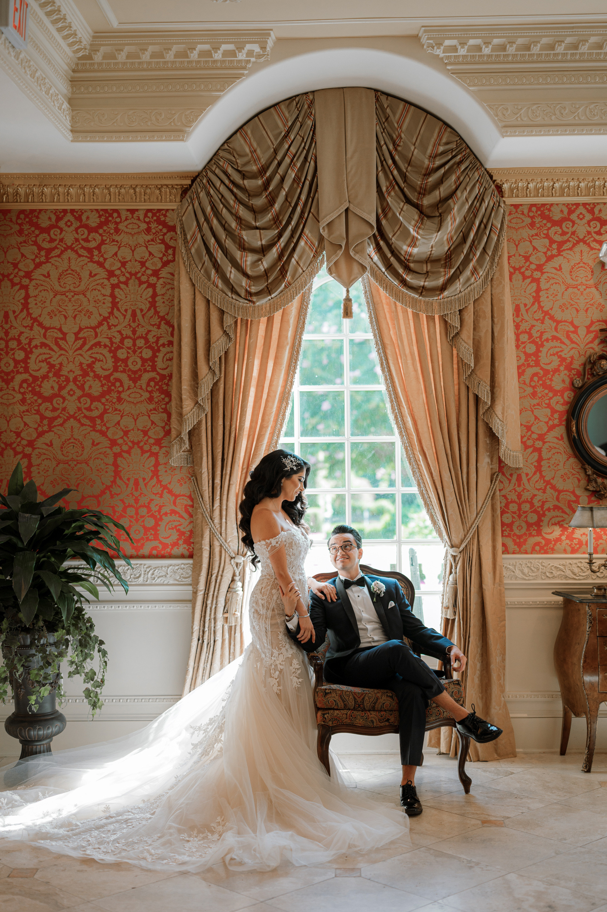 a bride and groom sitting in a chair in a room