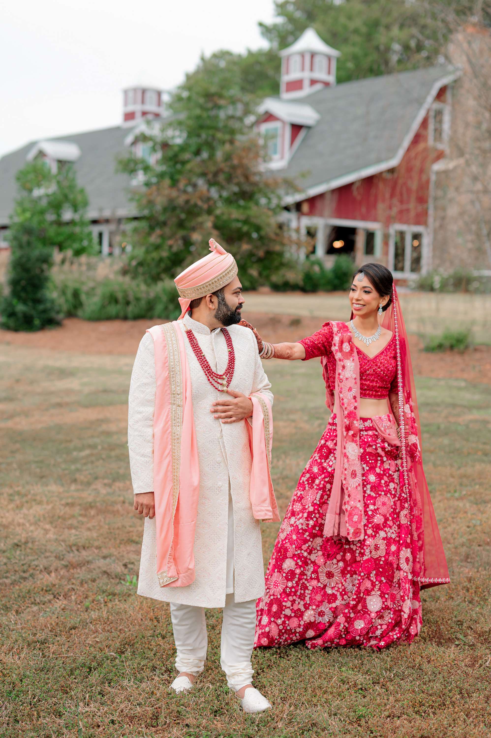 a bride and groom in front of a red barn