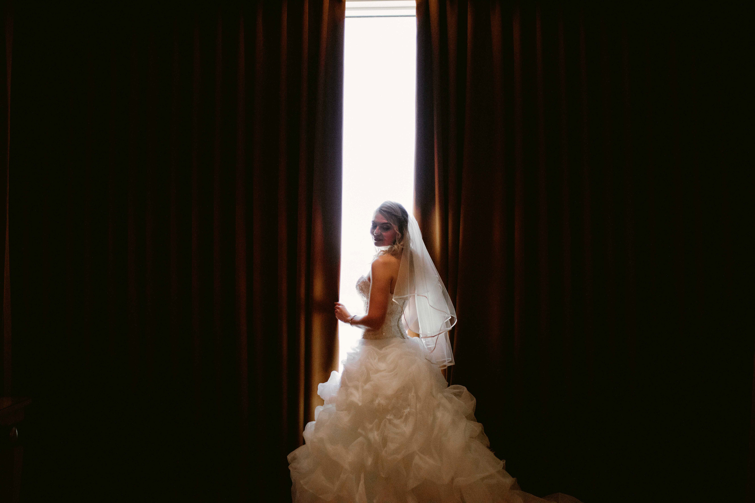 a bride in a wedding dress standing in front of a window
