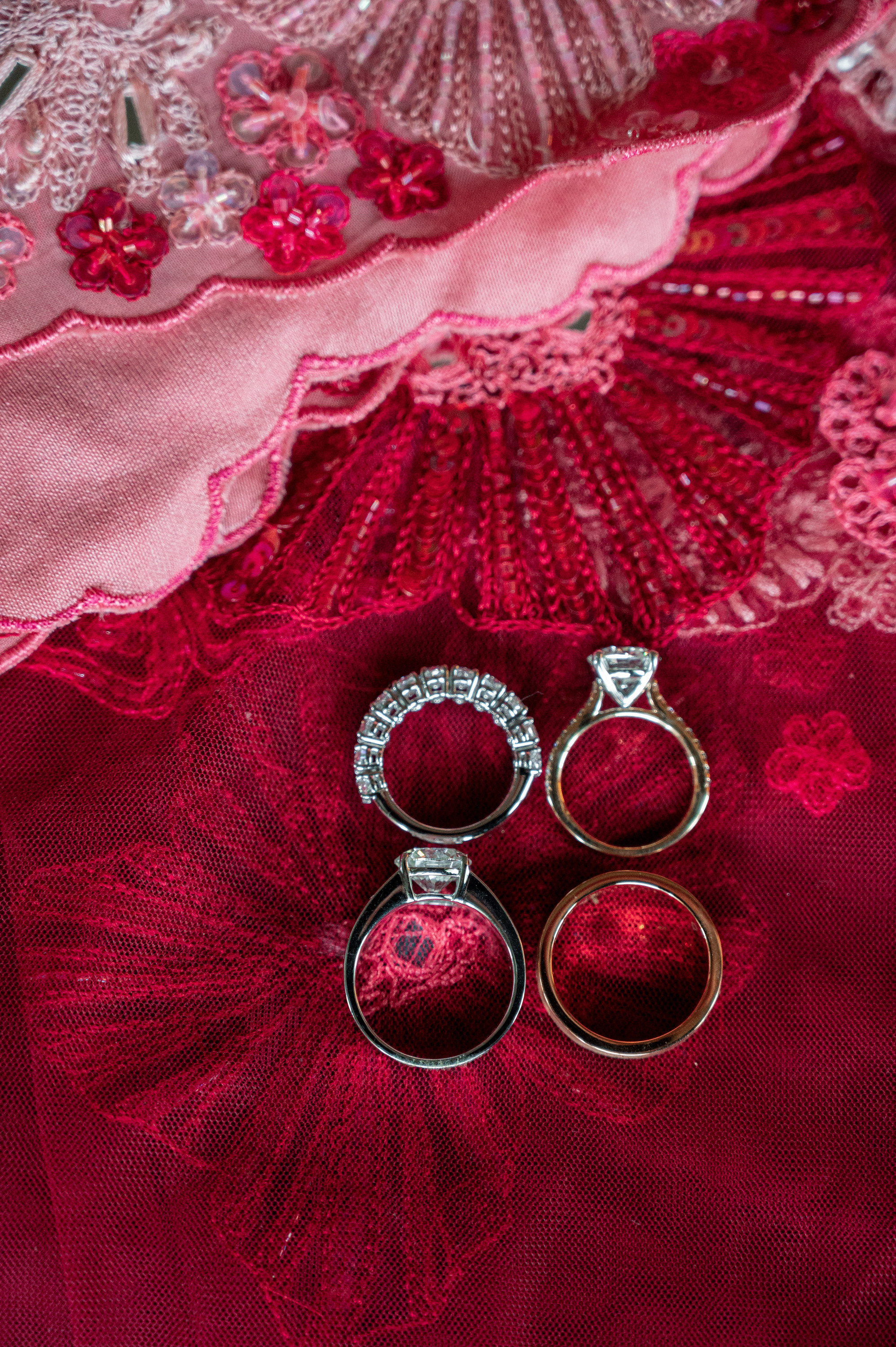 a pair of wedding rings on a red lace