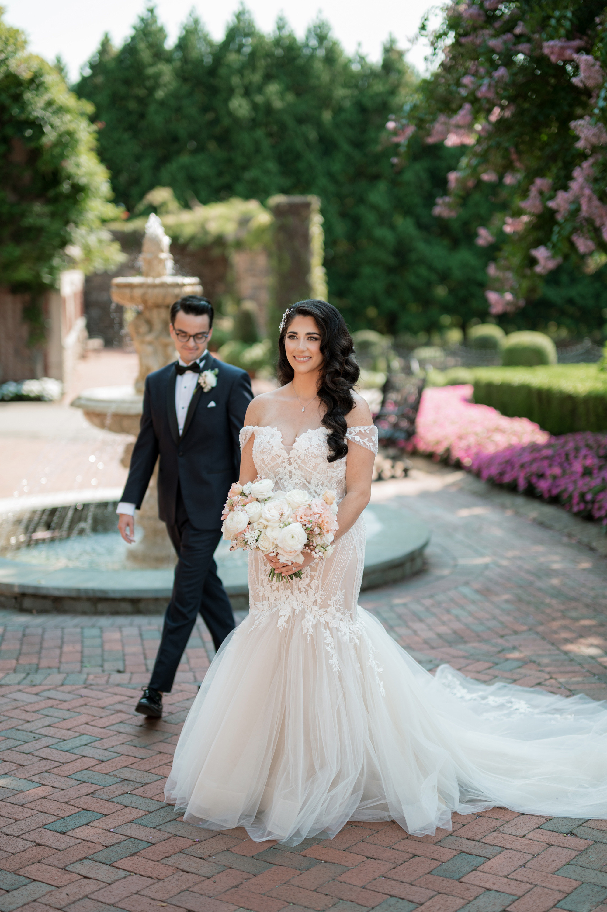 a bride and groom walking through the gardens at their wedding