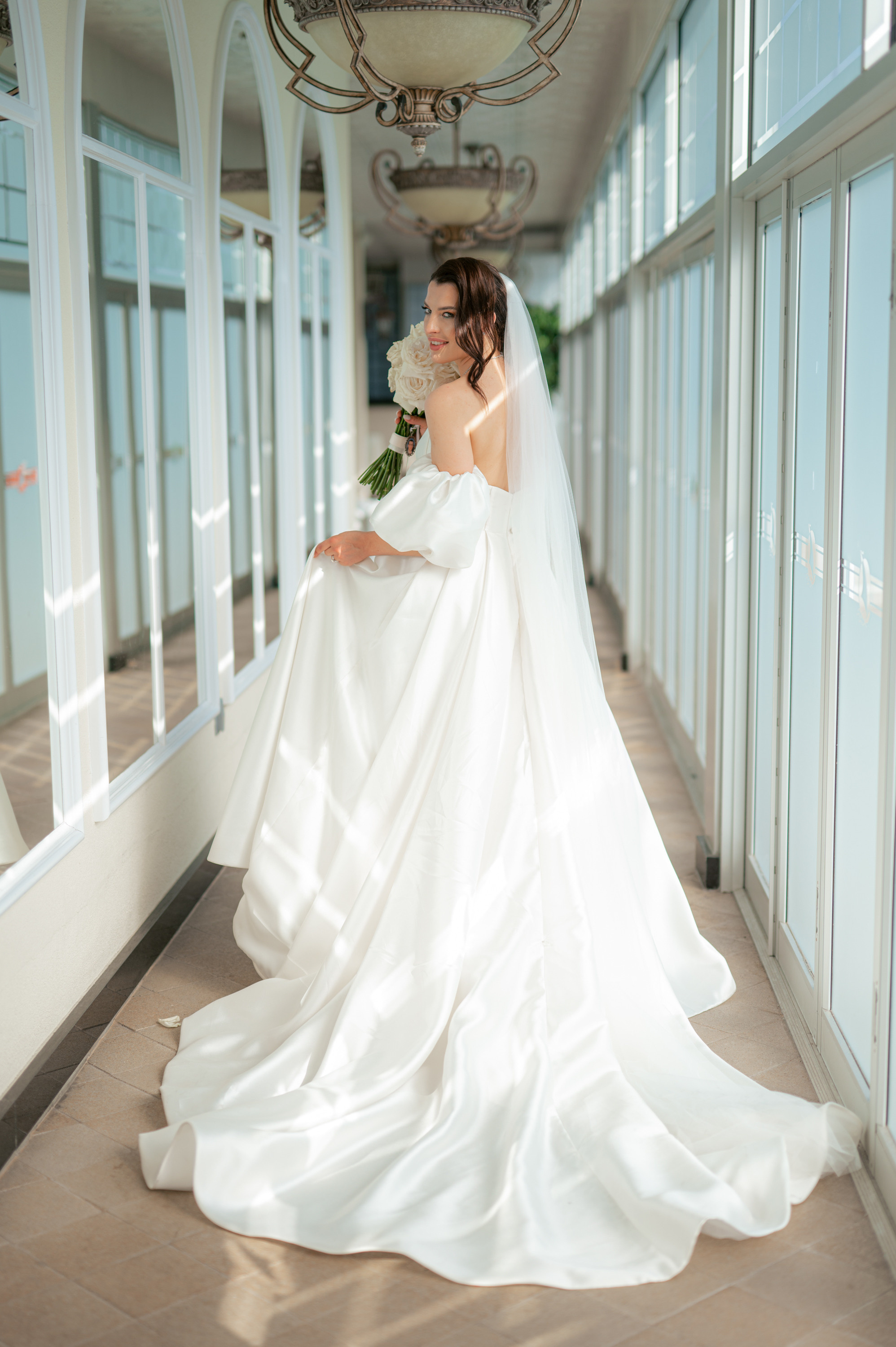 a bride in a white wedding dress standing in a hallway