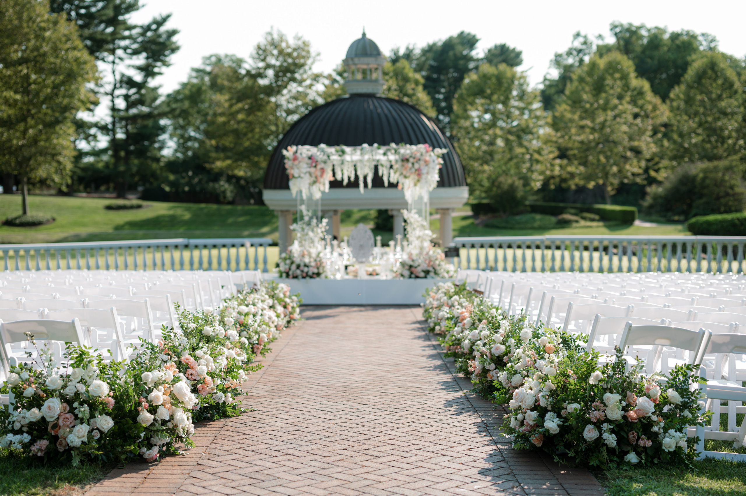 a wedding ceremony with white chairs and flowers