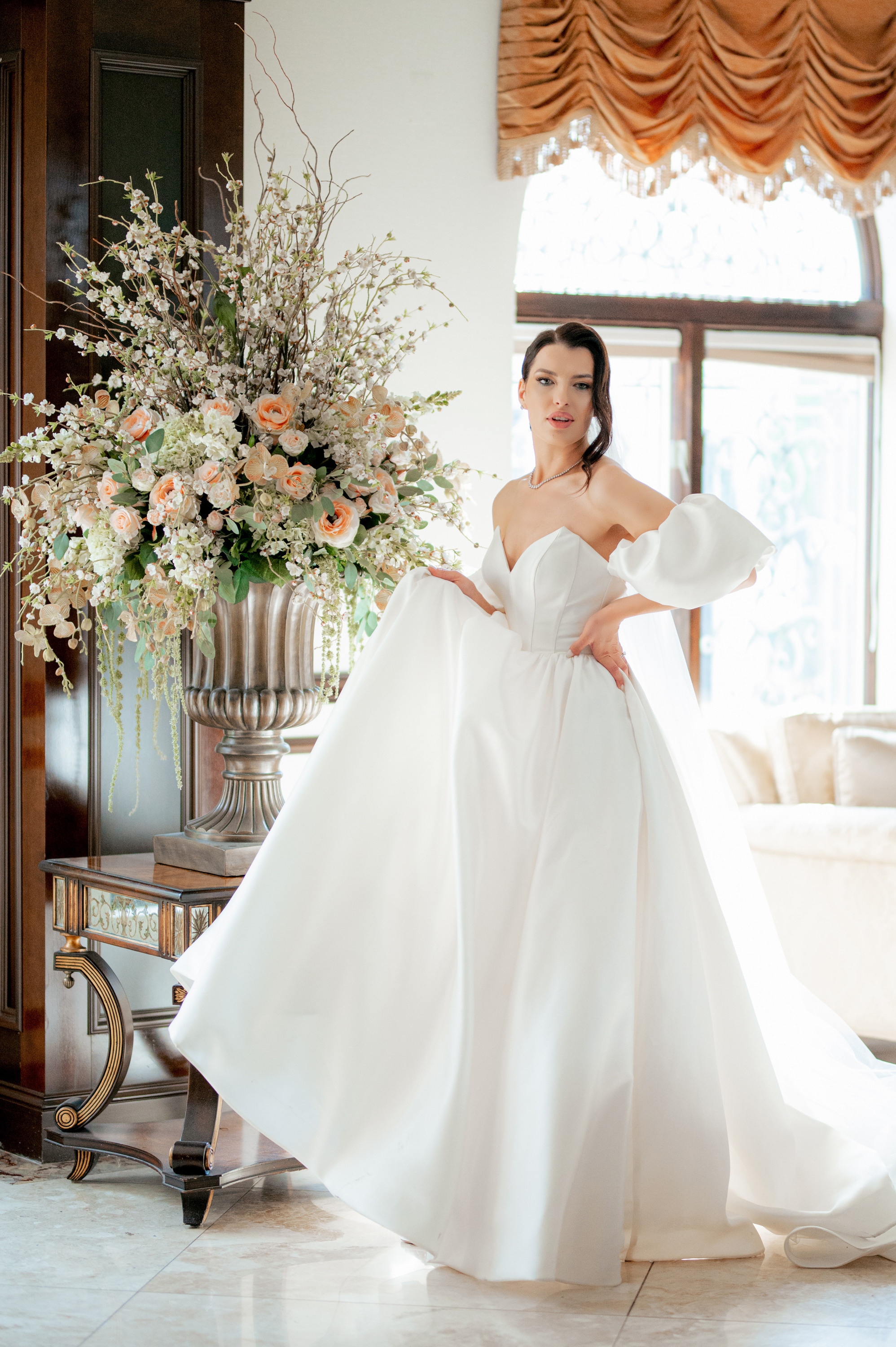 a woman in a white dress standing in front of a large vase of flowers