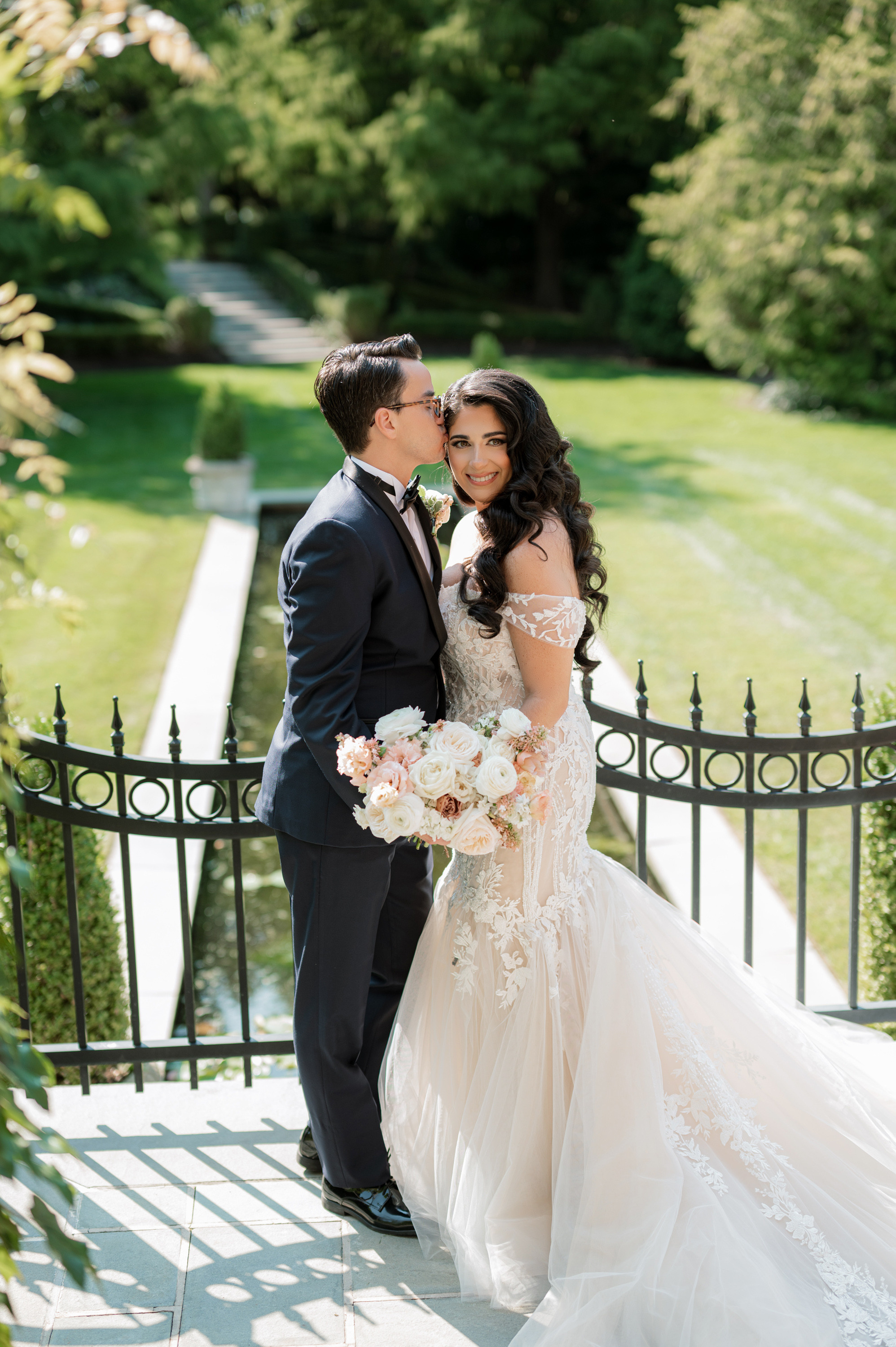 a bride and groom kissing on a bridge