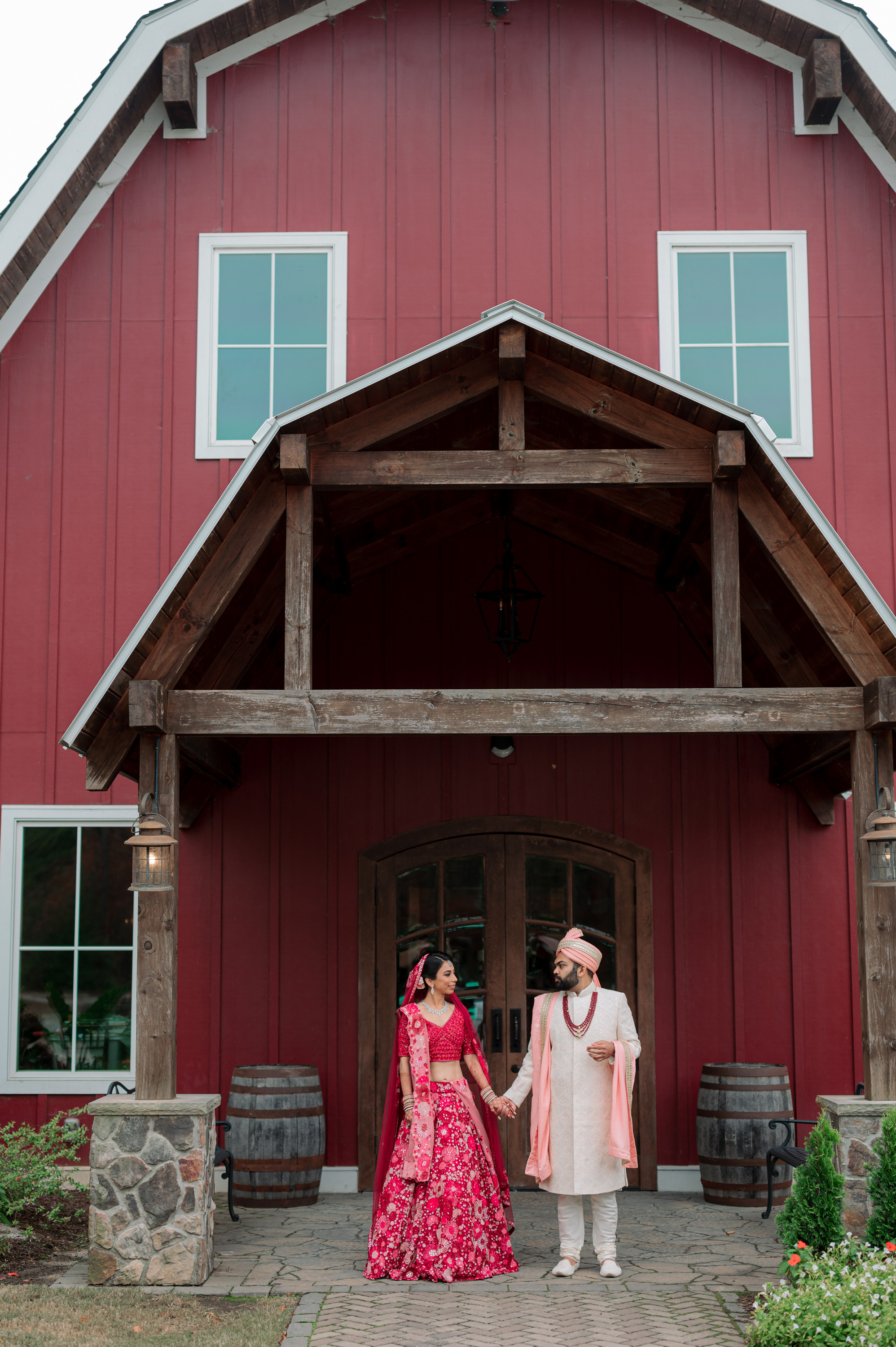 a couple standing in front of a red barn