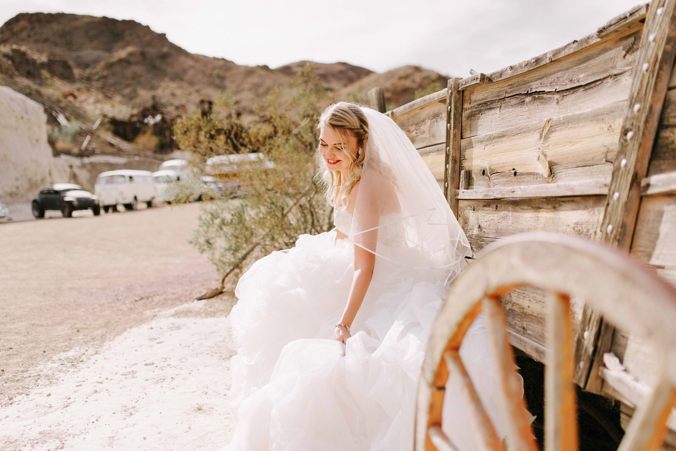 a bride sitting on a bench in the desert