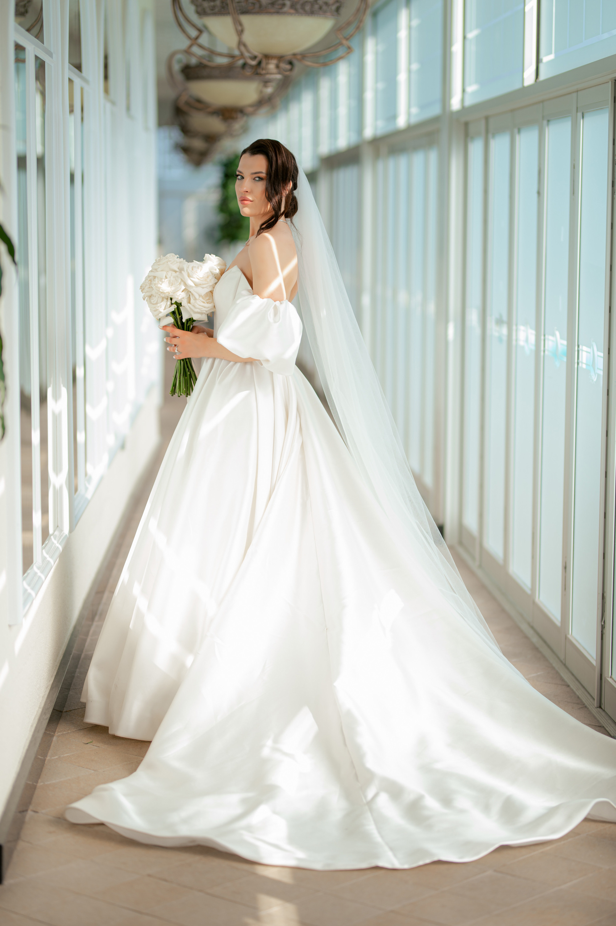 a bride in a white wedding dress standing in a hallway