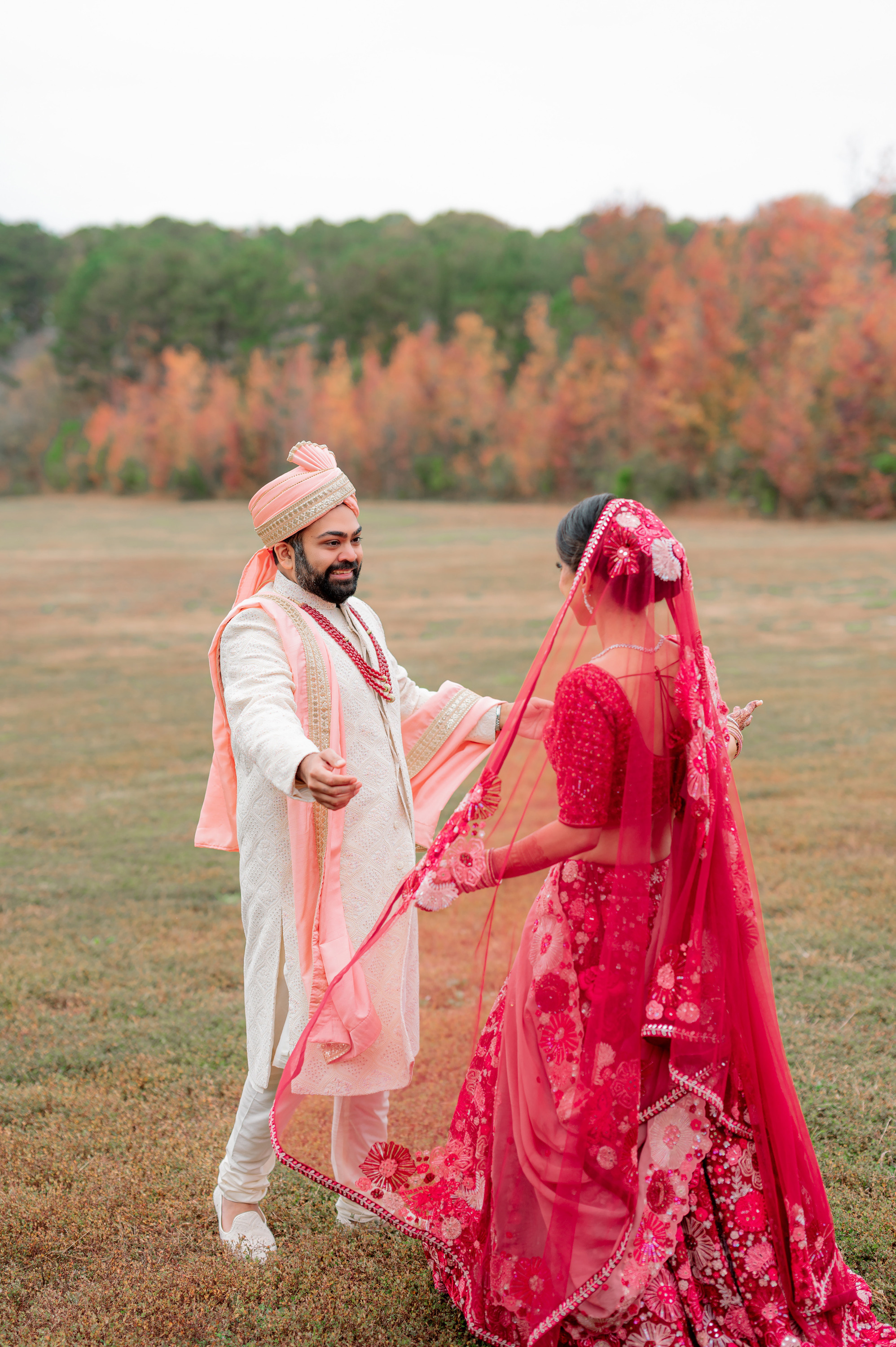 a bride and groom in a field with fall foliage