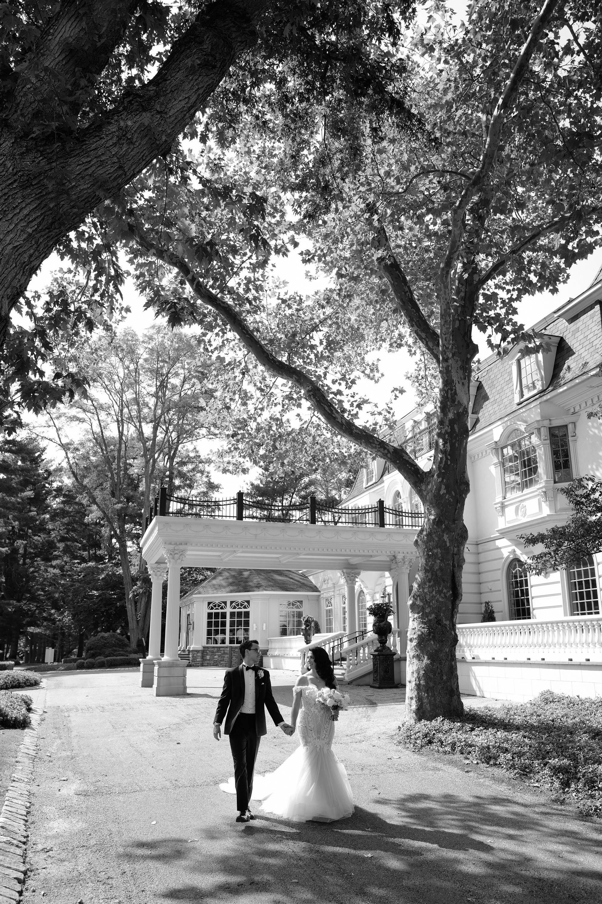 a bride and groom walking in front of a large tree