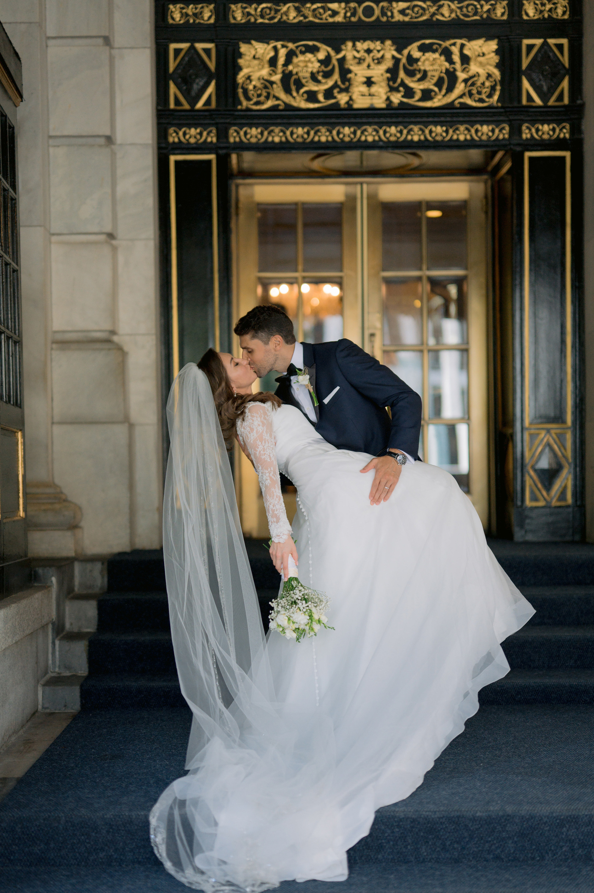 a bride and groom kissing in front of a building