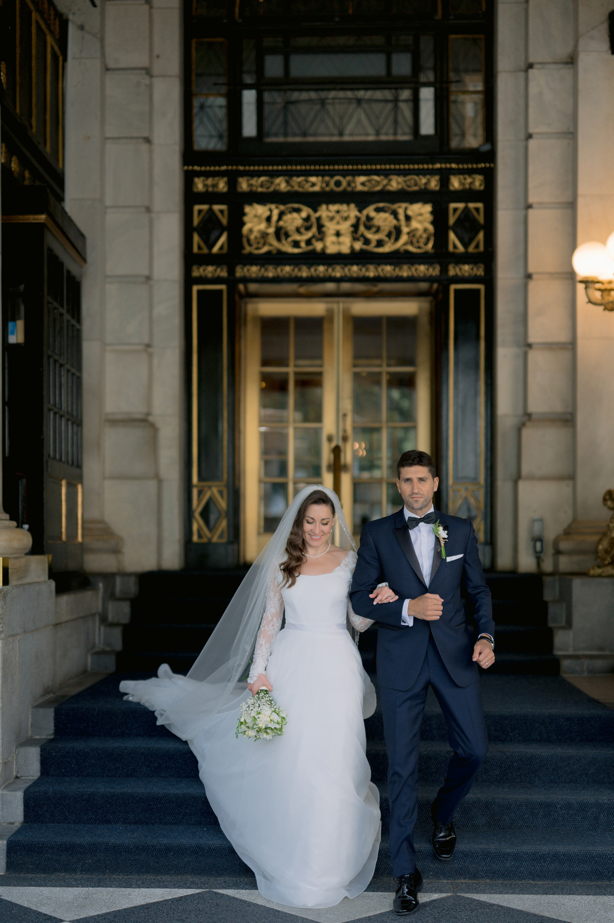 a bride and groom walking down the stairs