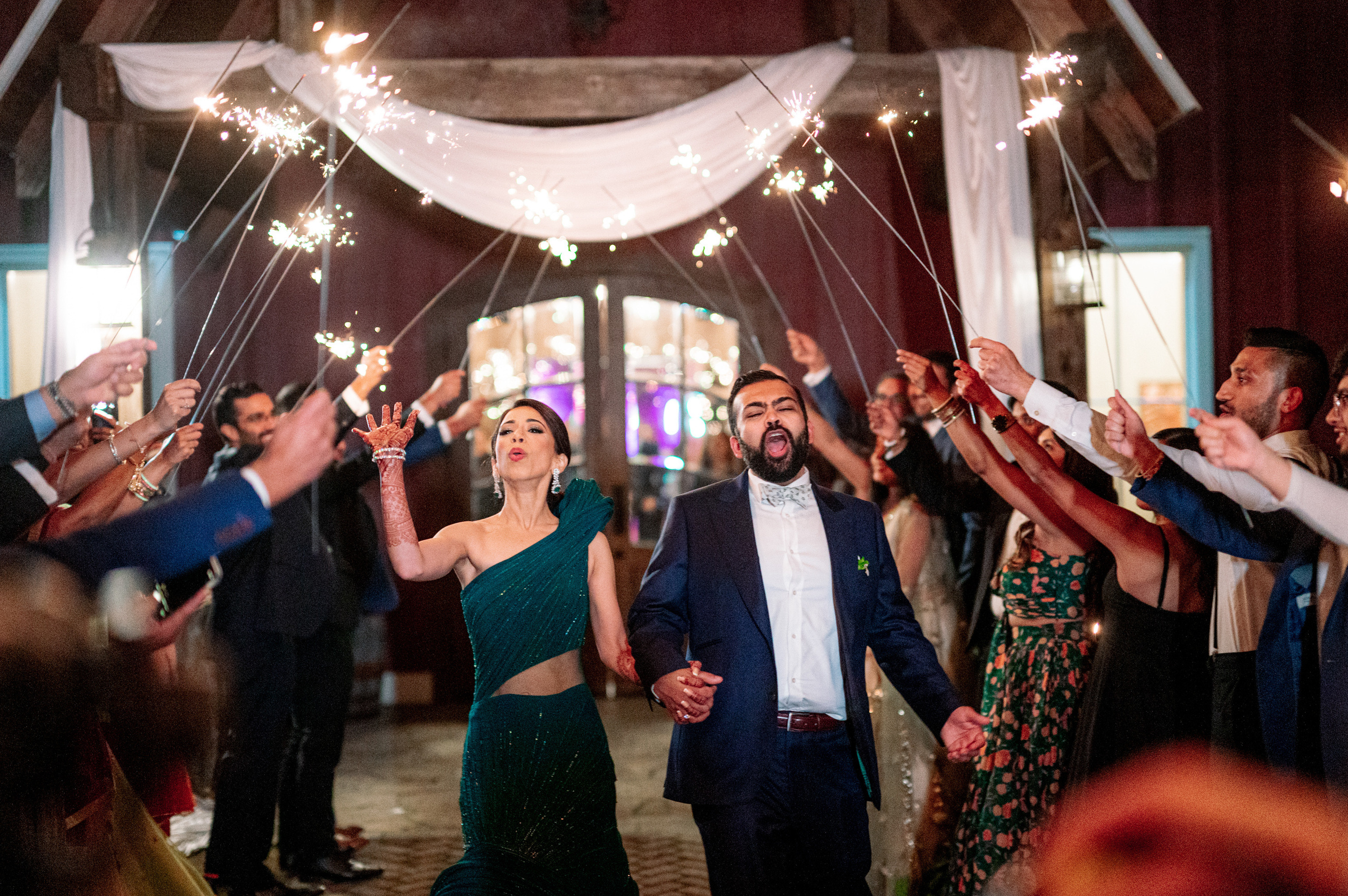 a couple holding sparkle sticks and walking through a crowd