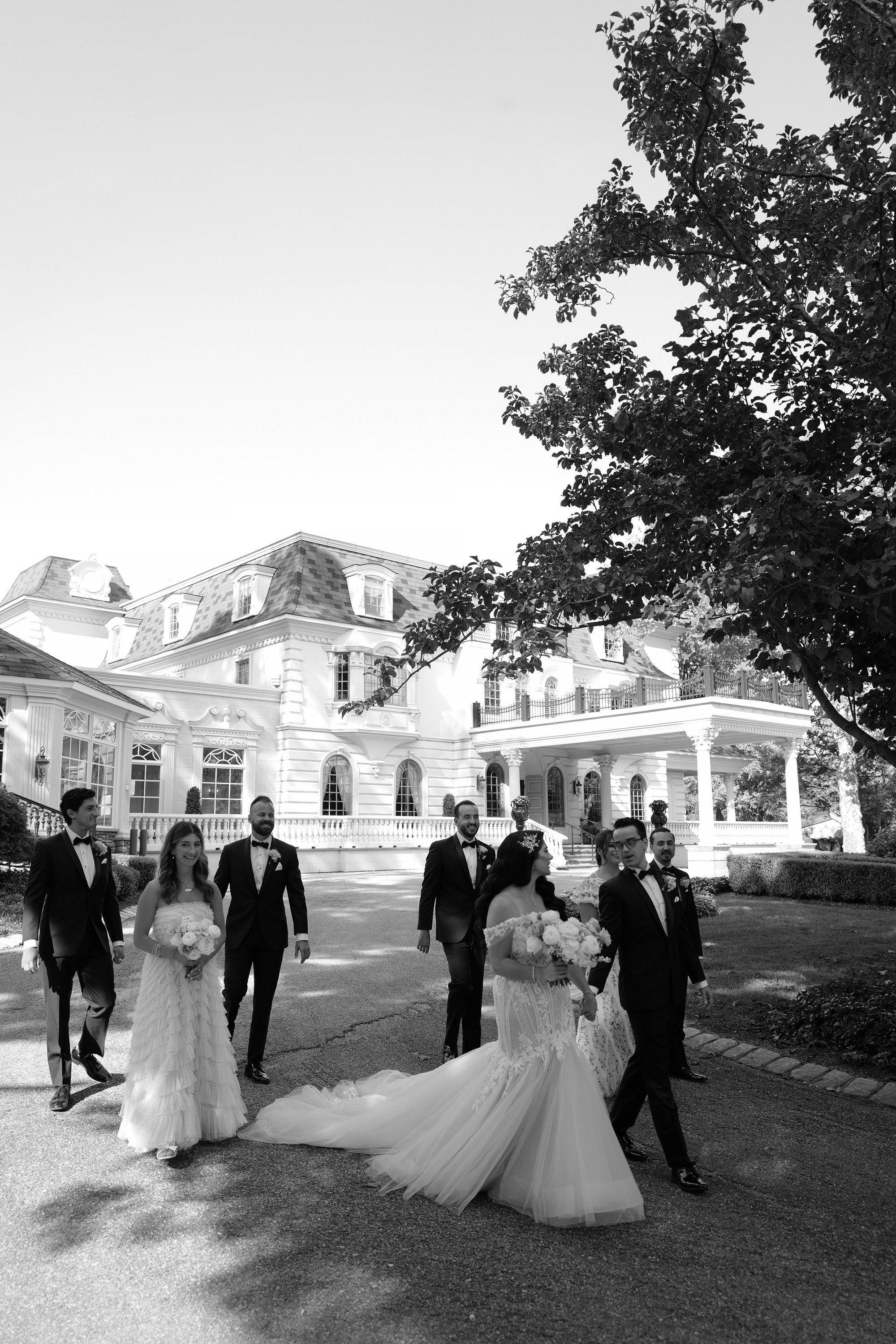 a bride and groom walking in front of a large mansion