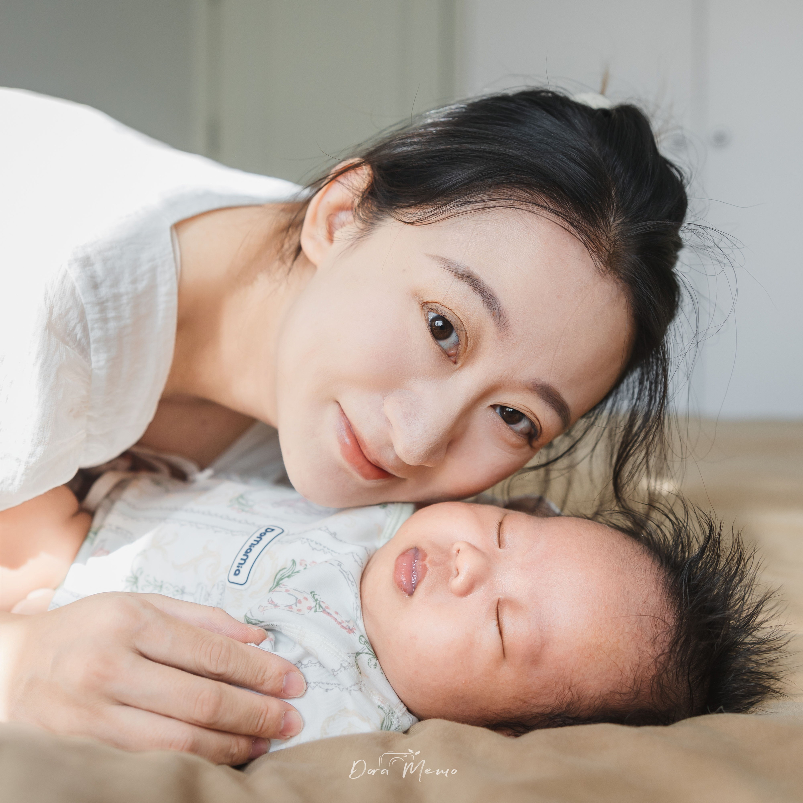 Mother lying beside her sleeping newborn baby, capturing a quiet and intimate moment in a natural light family photography session in Shanghai.
