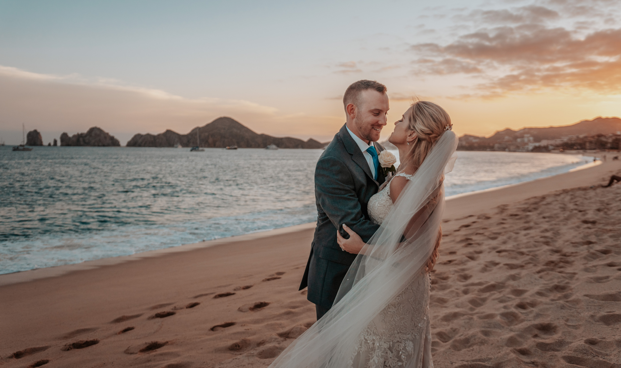 Bride and groom embracing on the shore of Los Cabos at golden hour