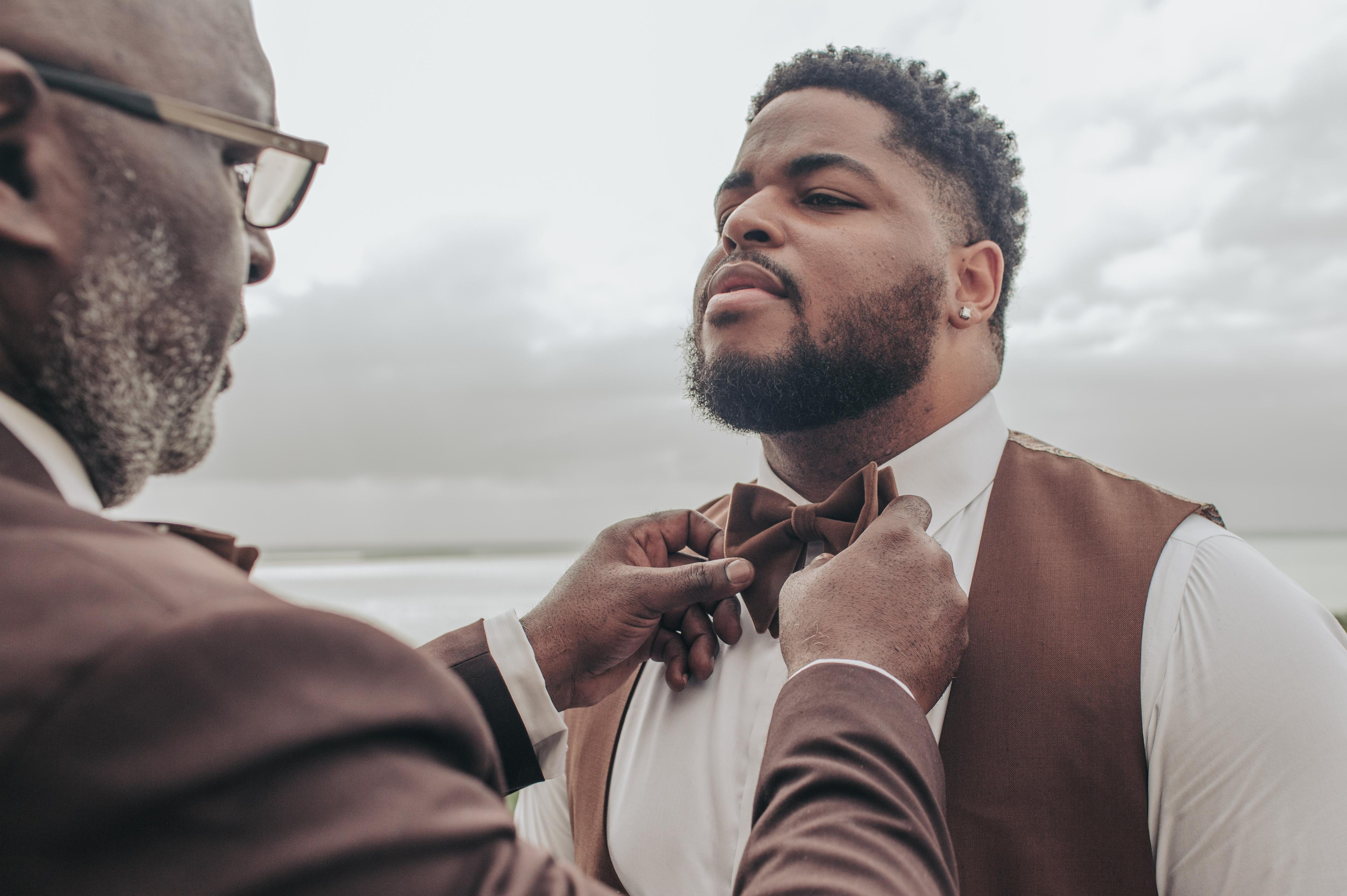 Candid detail photo of groom’s hands tying his tie