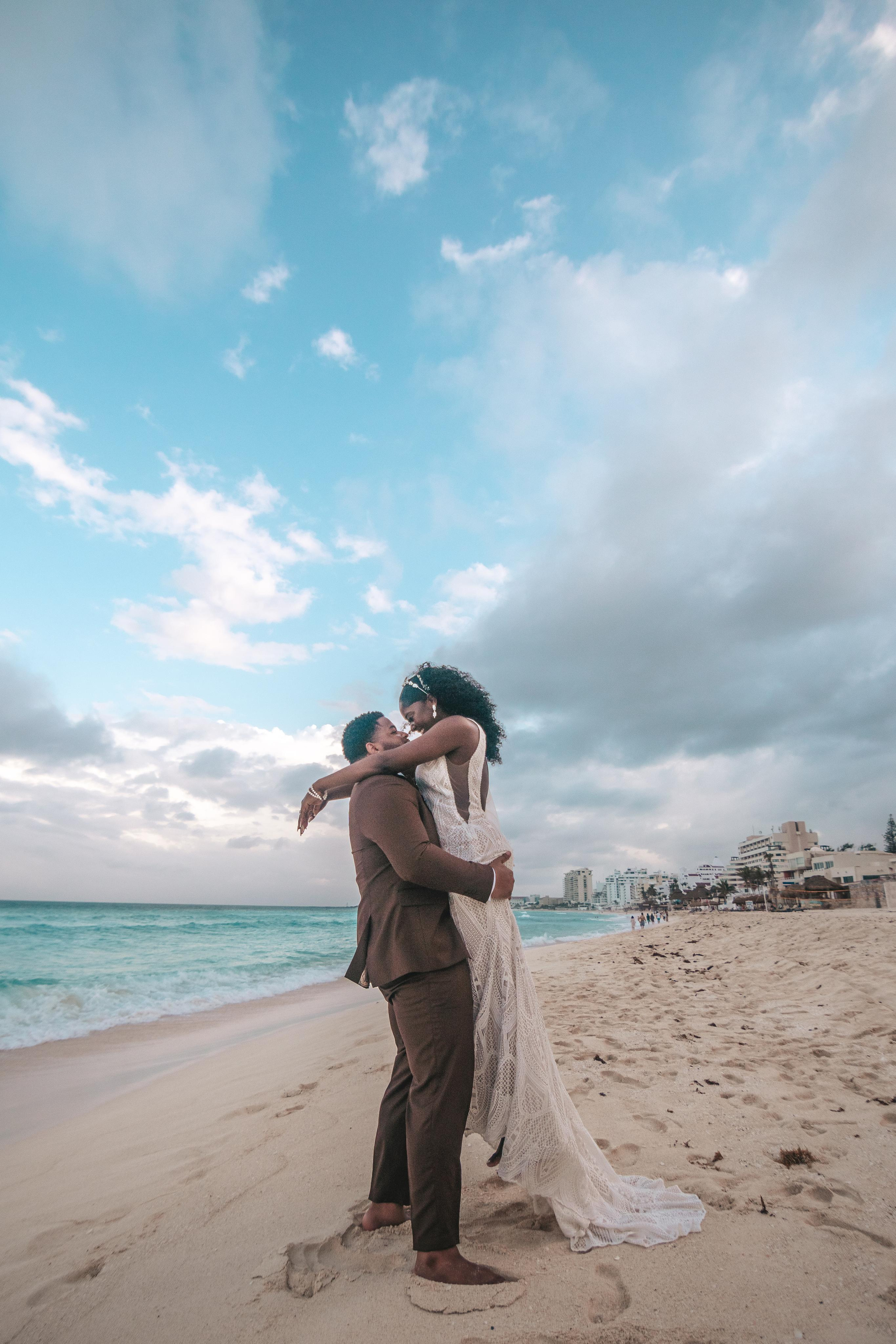 Moody sky, warm hearts – candid beach kiss captured by wedding photographer