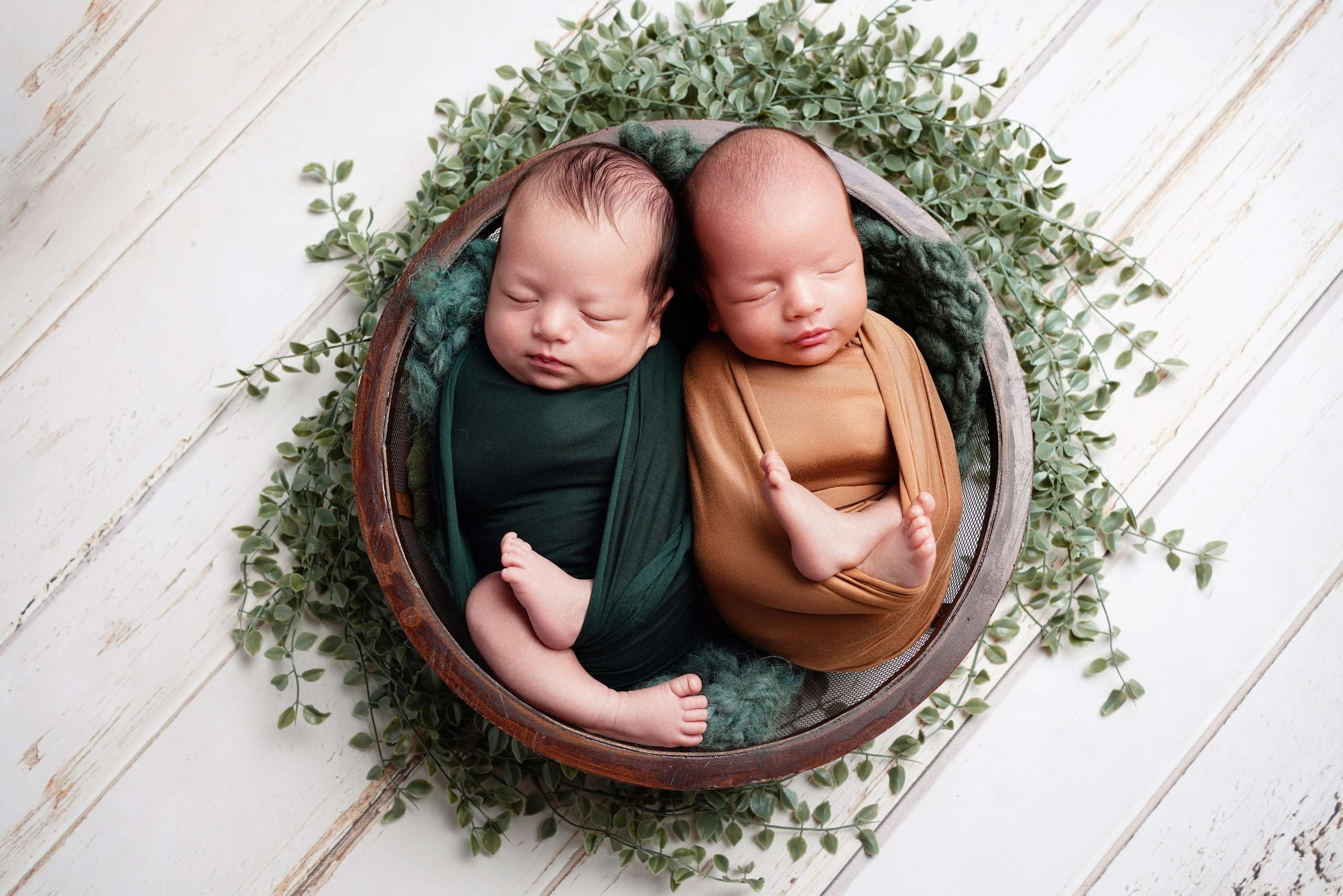 Zwillinge kuscheln eng umarmt in einem Kinderwagen, in Decken gewickelt