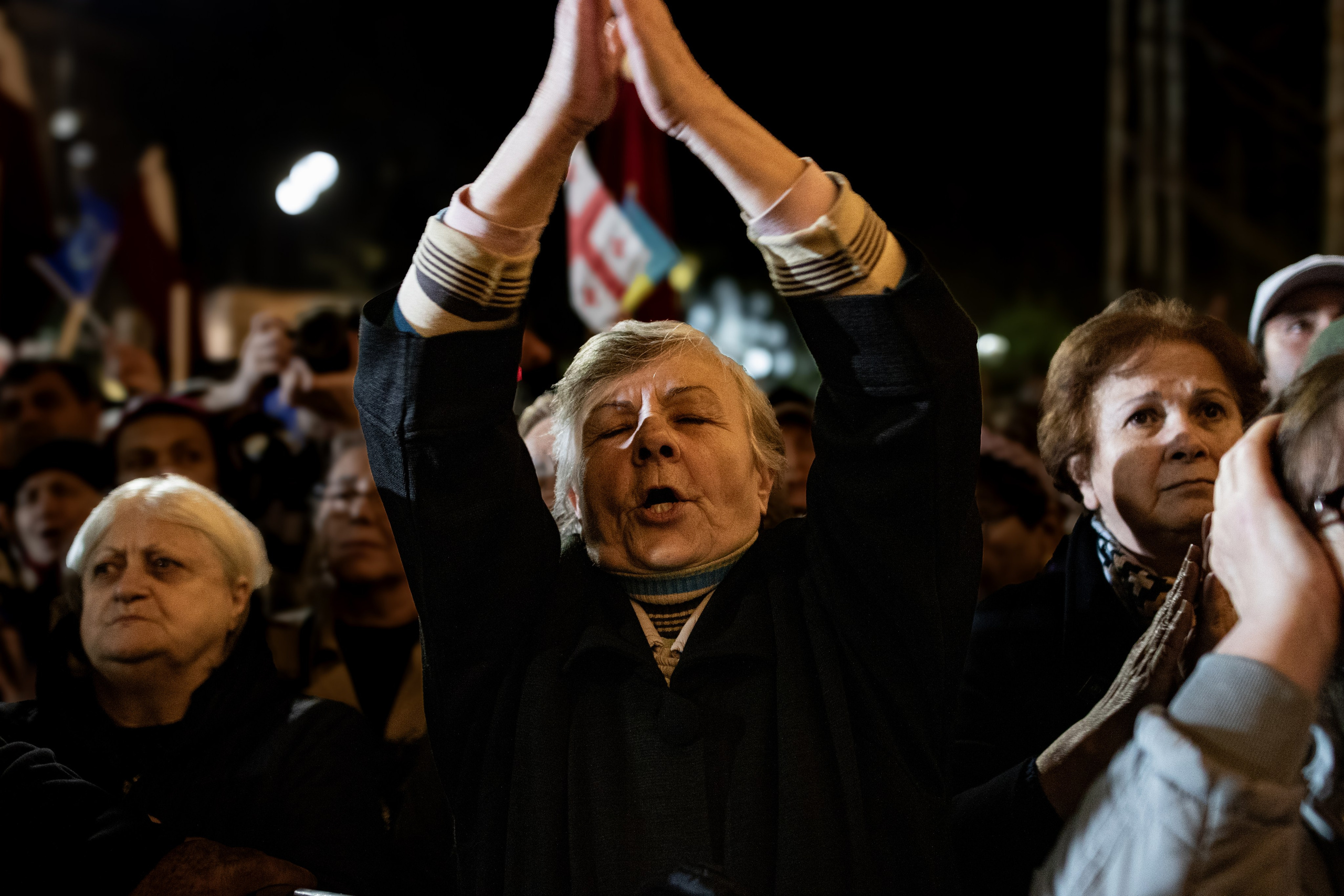 Une femme de l’opposition, écoutant avec émotion les discours de la présidente Salomé Zourabichvili, symbole des divisions politiques qui traversent la Géorgie en cette période électorale.