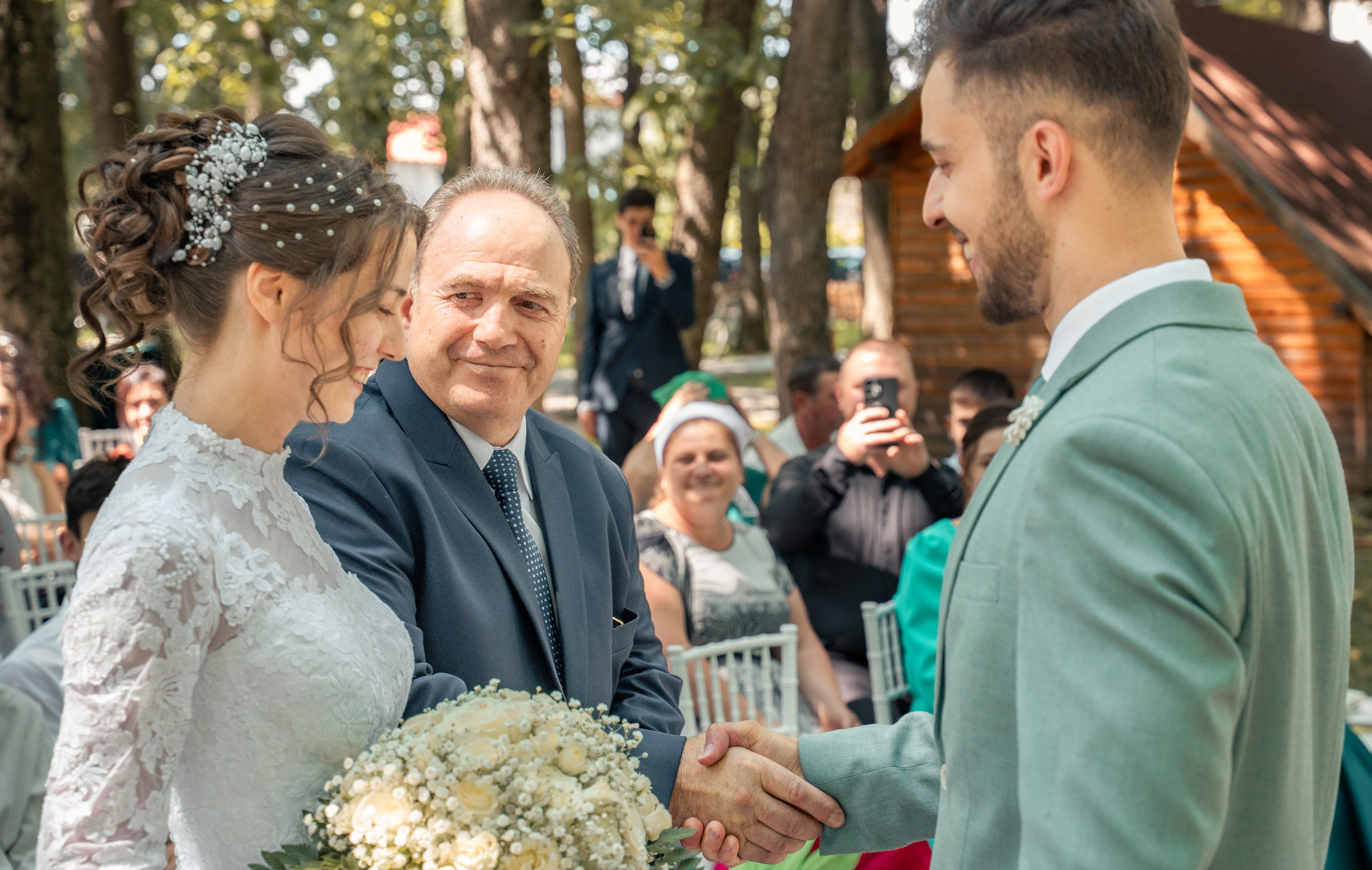 Mire dând mâna cu tatăl miresei la altar, ceremonie în aer liber, moment de respect și familie, fotografii autentice de nuntă București, incadru.ro.