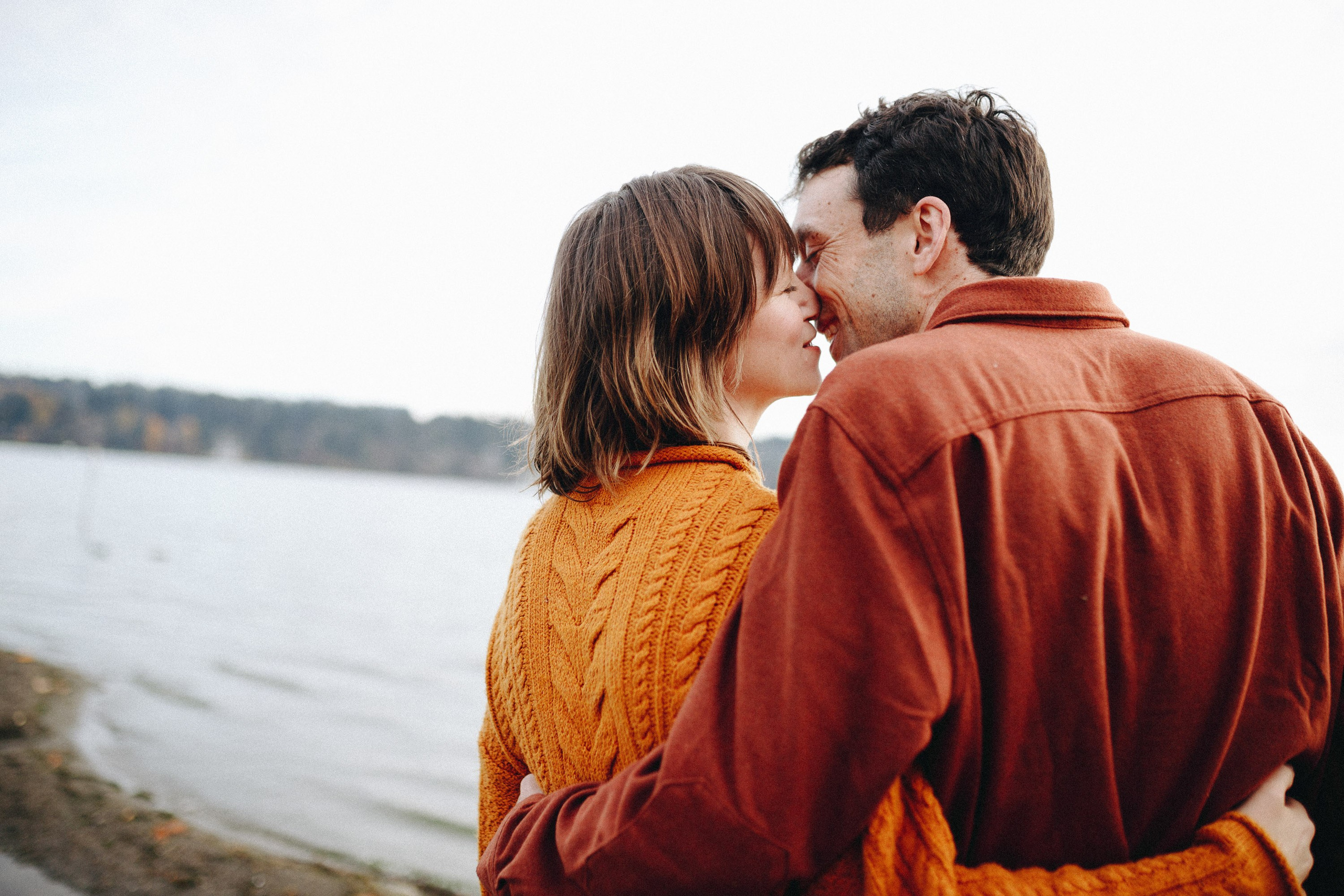 Couple hugging by the lake, cozy outdoor moment