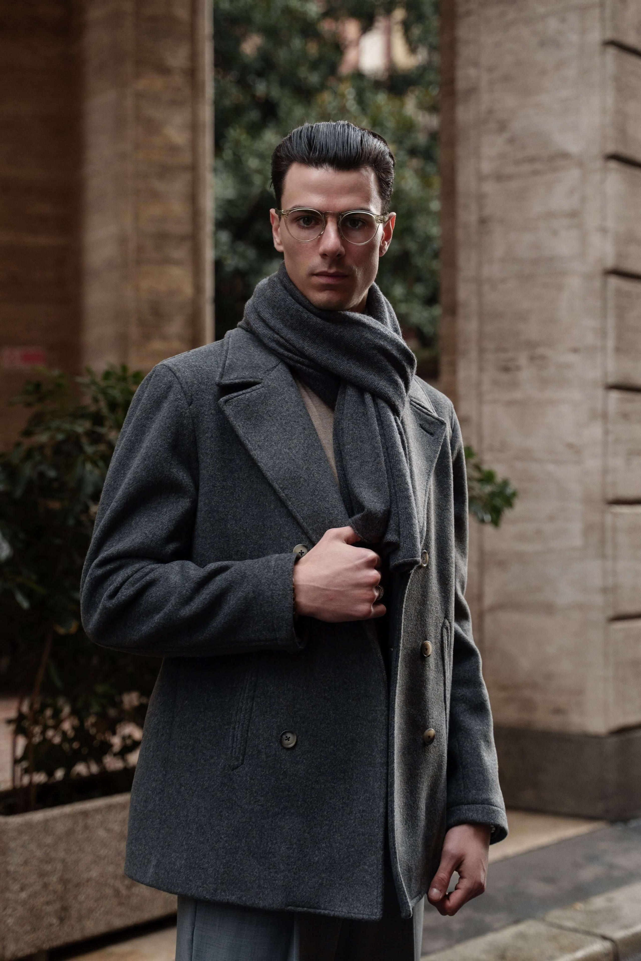 Fashion portrait of a man in silver glasses and gray wool coat with scarf in Milan
