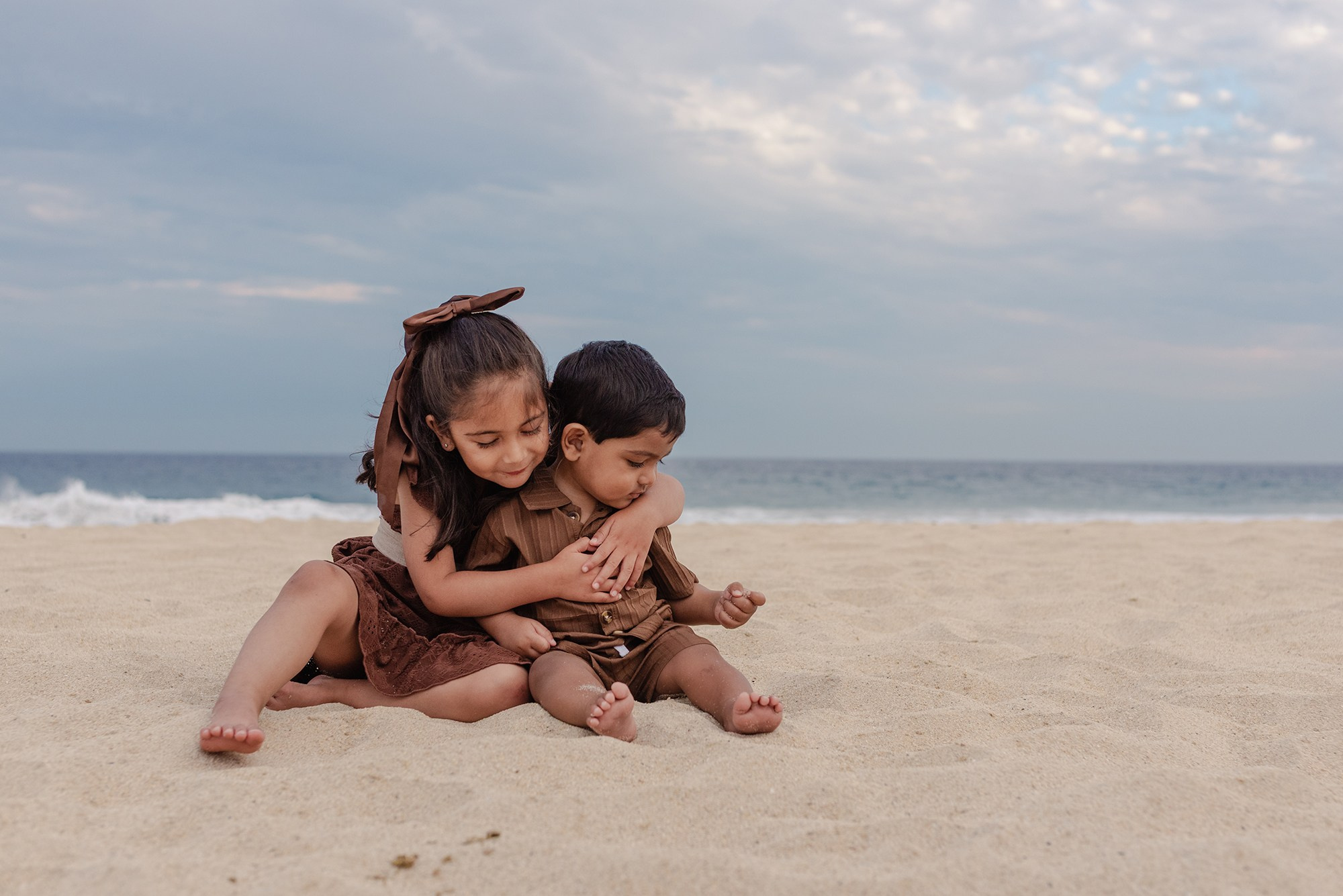 Big sister hugging her baby brother on the sand at Hyatt Ziva Los Cabos