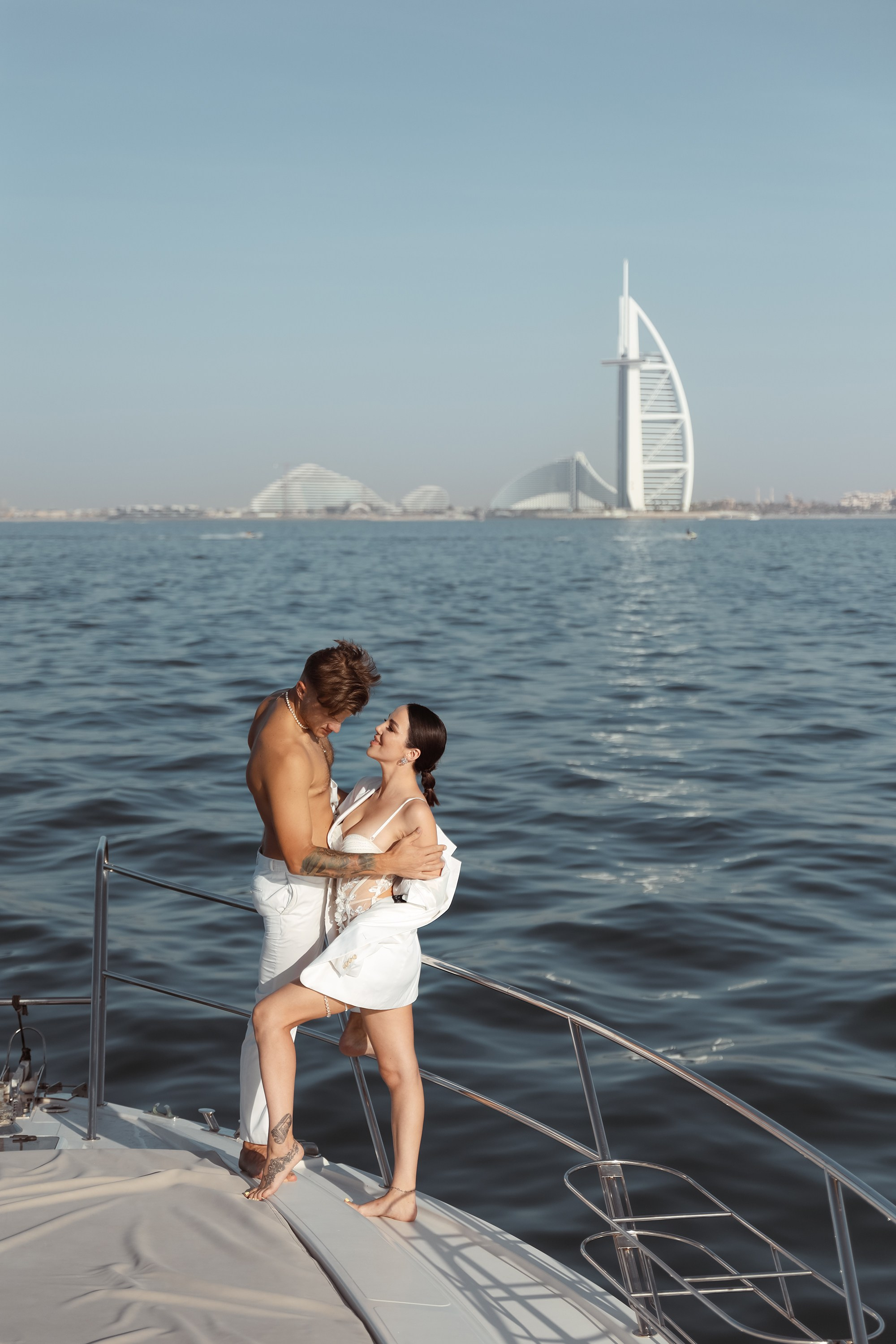 Two lovers hold each other close on a yacht, their connection palpable as the golden sunlight reflects off the calm waters around them. Dubai, United Arab Emirates