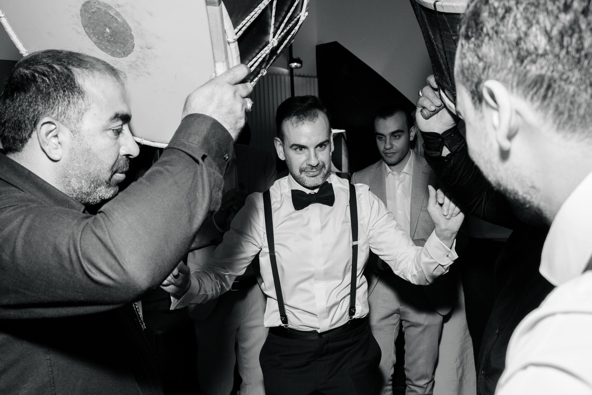 Black and white photo of the groom celebrating with guests on the dance floor, energetic party moment at a Munich wedding reception photographed by Inna Zaytseva